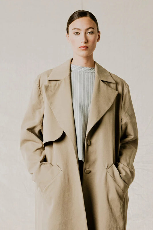 Close-up view on model of District Trench Coat in Beige by Bodybag by Jude — oversized Tencel-cotton trench with removable belt, available in Kelowna at Textile Apparel