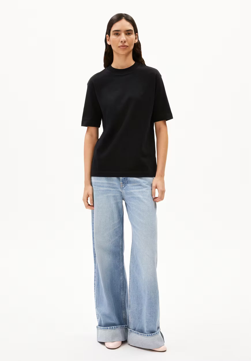 Person wearing a black t-shirt and light blue jeans on a white background