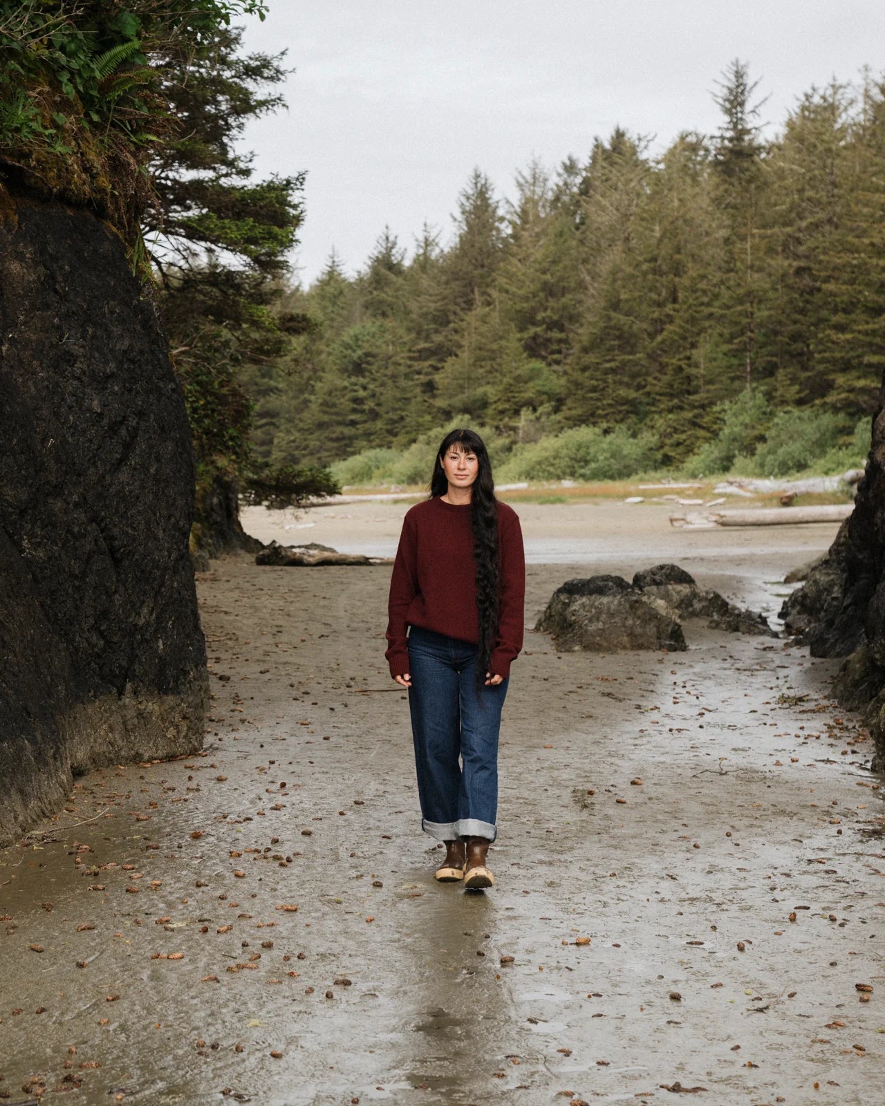Person standing on a beach with forest in the background