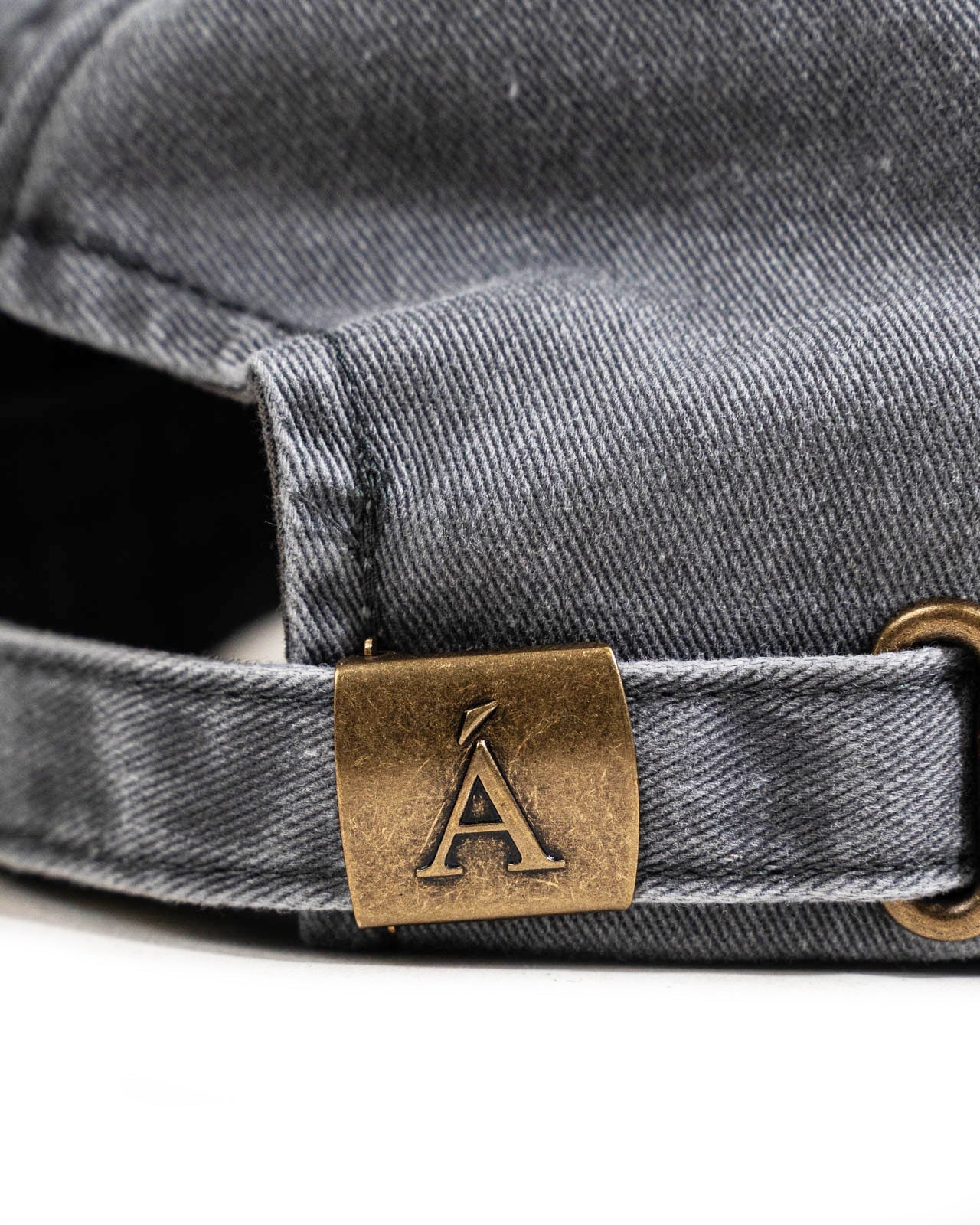 Closeup of gray denim Anian hat adjustable back strap with brass logo buckle and stitching in Kelowna