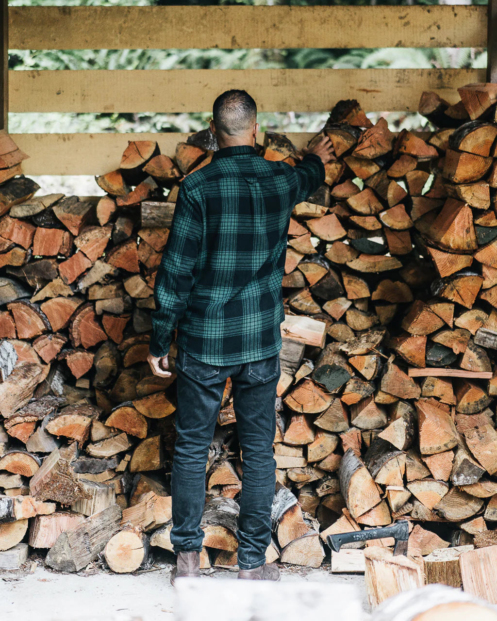Man wearing a men's plaid flannel shirt while stacking firewood in a rustic setting unisex in Kelowna