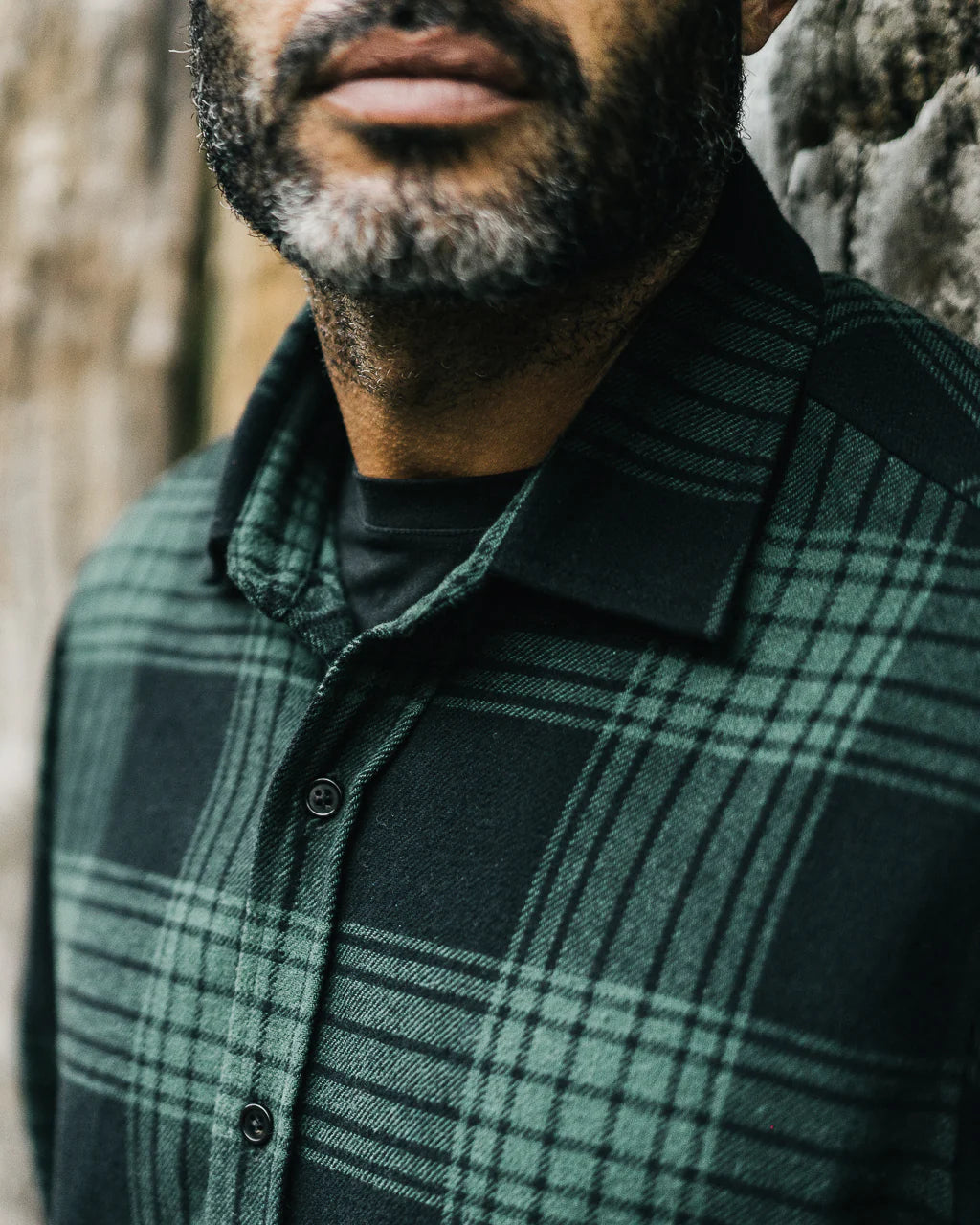 Close-up of a man wearing a green and black men's plaid flannel shirt with button details in Kelowna