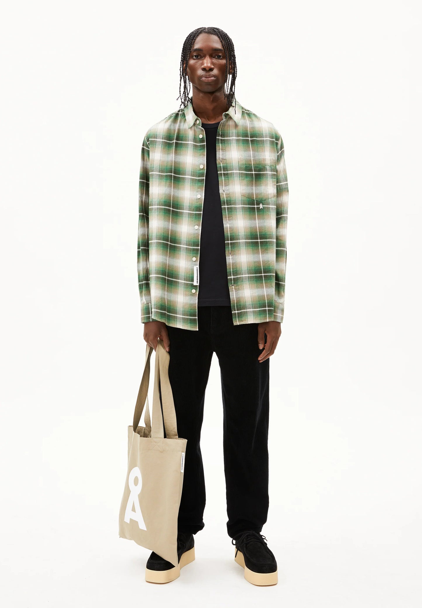 Men's long sleeve plaid shirt from ARMEDANGELS Canada in green plaid pattern, styled with black pants and a tote bag in Canada