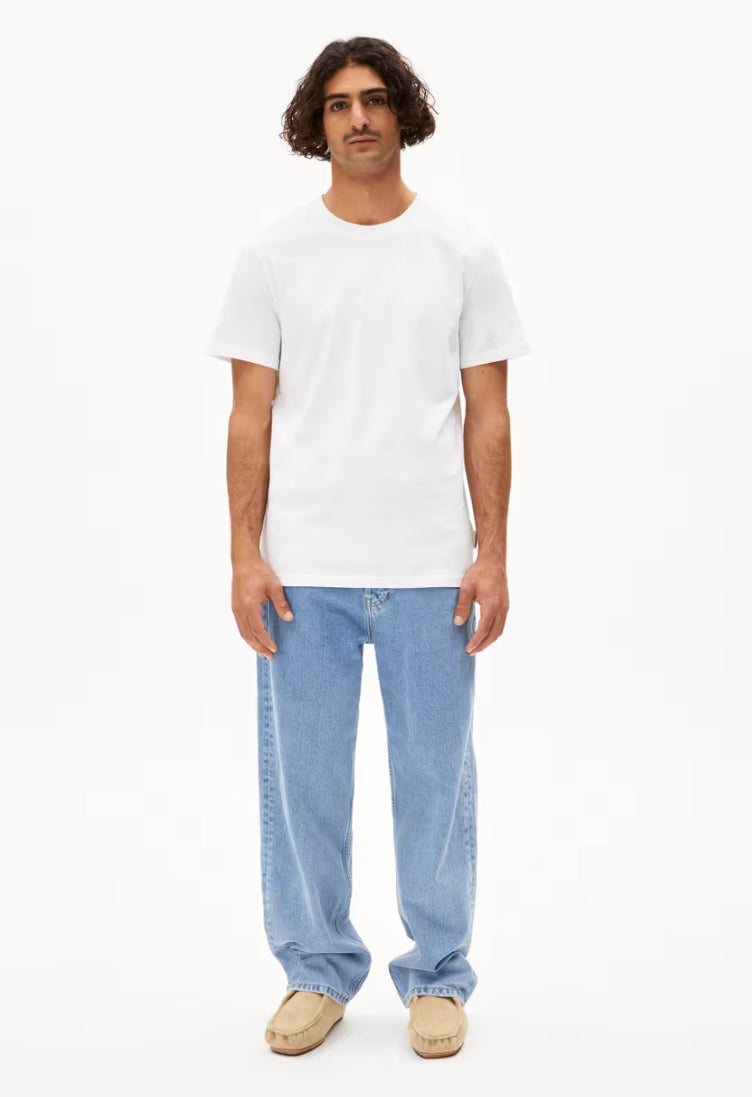 Man wearing ARMEDANGELS Canada MAARKOS White T-shirt paired with light blue jeans and beige shoes in Kelowna