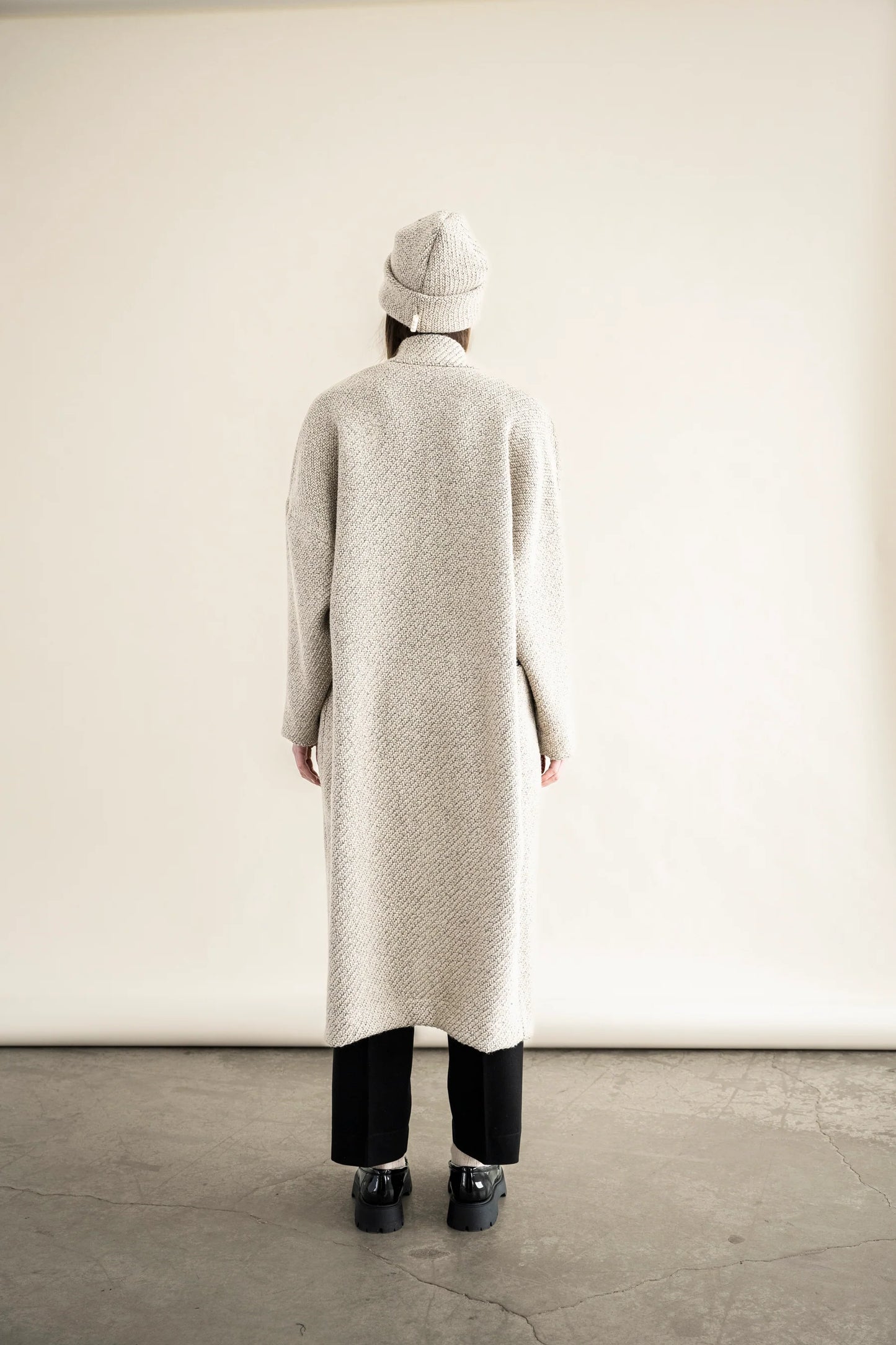 Back view of BodyBag by Jude long textured cream beige knit cardigan with matching beanie and black pants in Kelowna