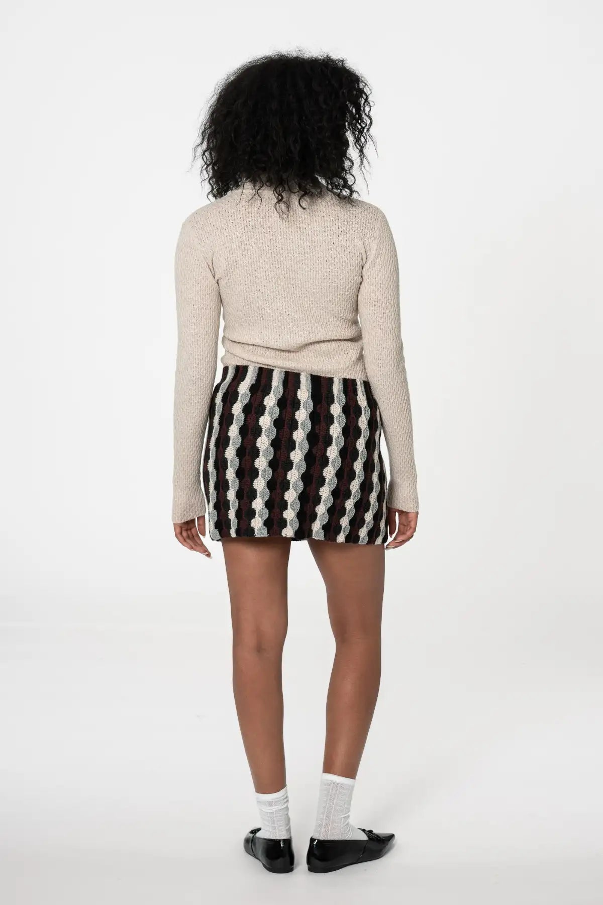 Dinadi merino turtleneck sweater in beige, paired with a patterned skirt for a stylish look in Kelowna and Canada