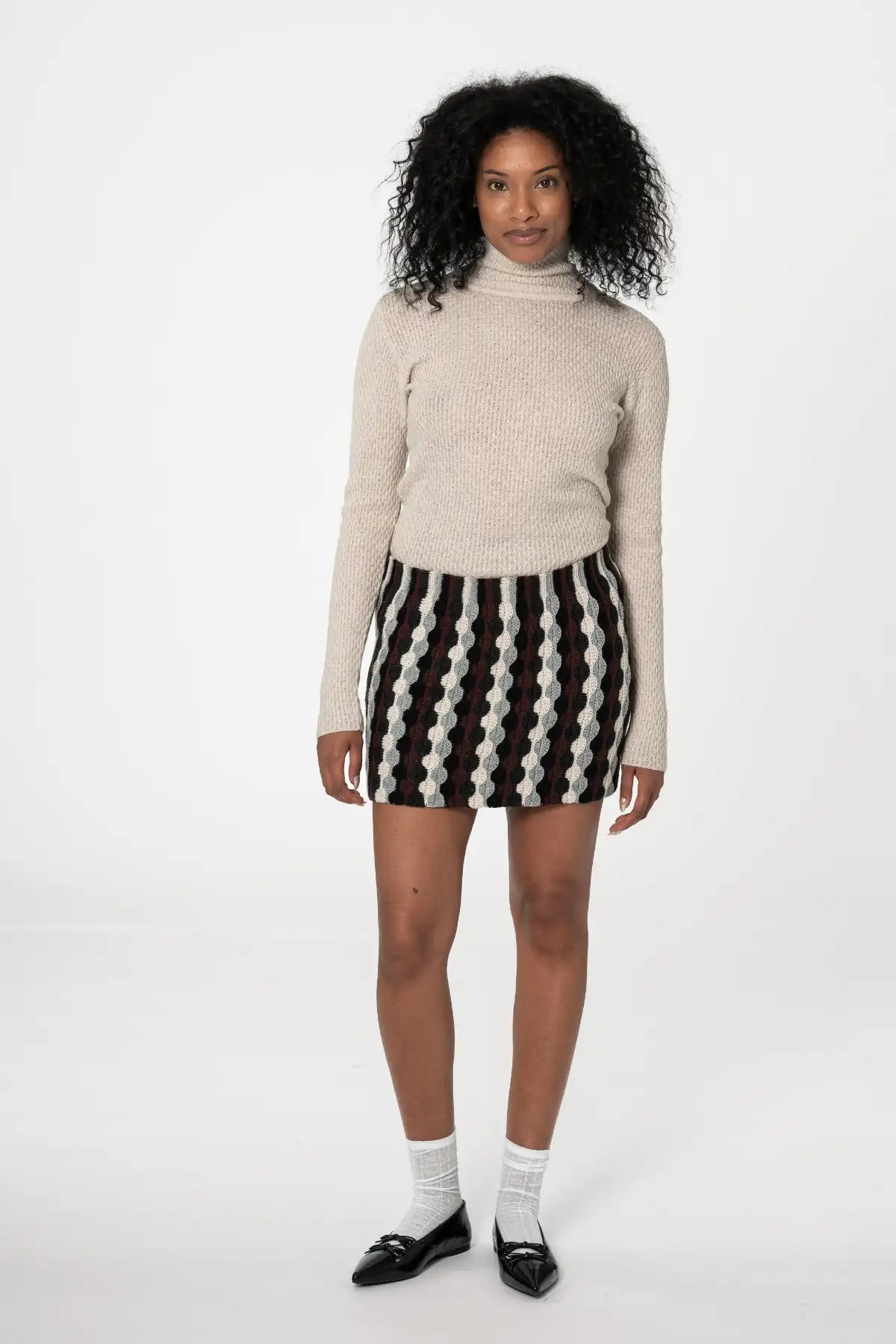 Dinadi merino turtleneck sweater in beige, styled with a patterned skirt for a chic look in Kelowna and Canada