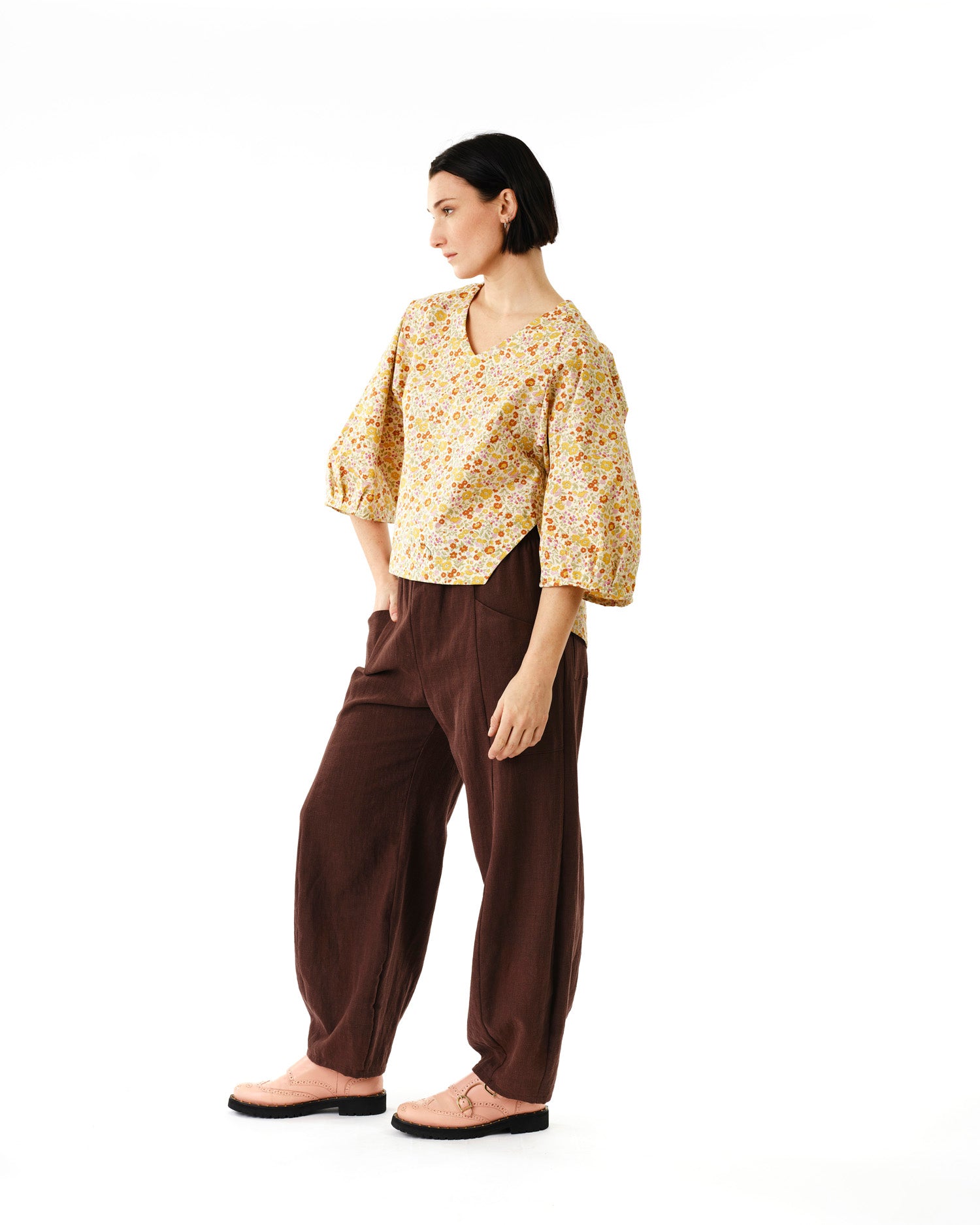 Jennifer Glasgow Design model wearing a floral yellow v neck blouse with balloon sleeves and relaxed brown linen pants in Kelowna