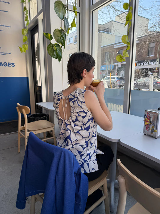 Marigold Montreal printed tank worn by woman in cafe with blue leaf print and back tie detail in Kelowna