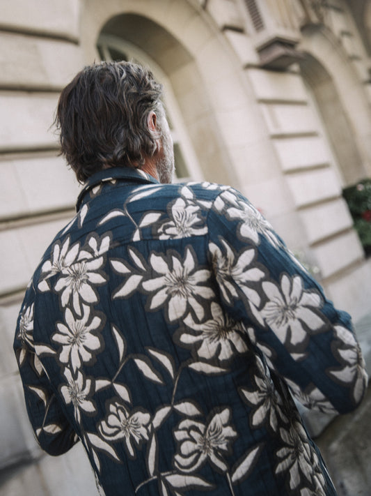 Man wearing vintage indigo overshirt with large white floral print seen from back near stone building in Kelowna