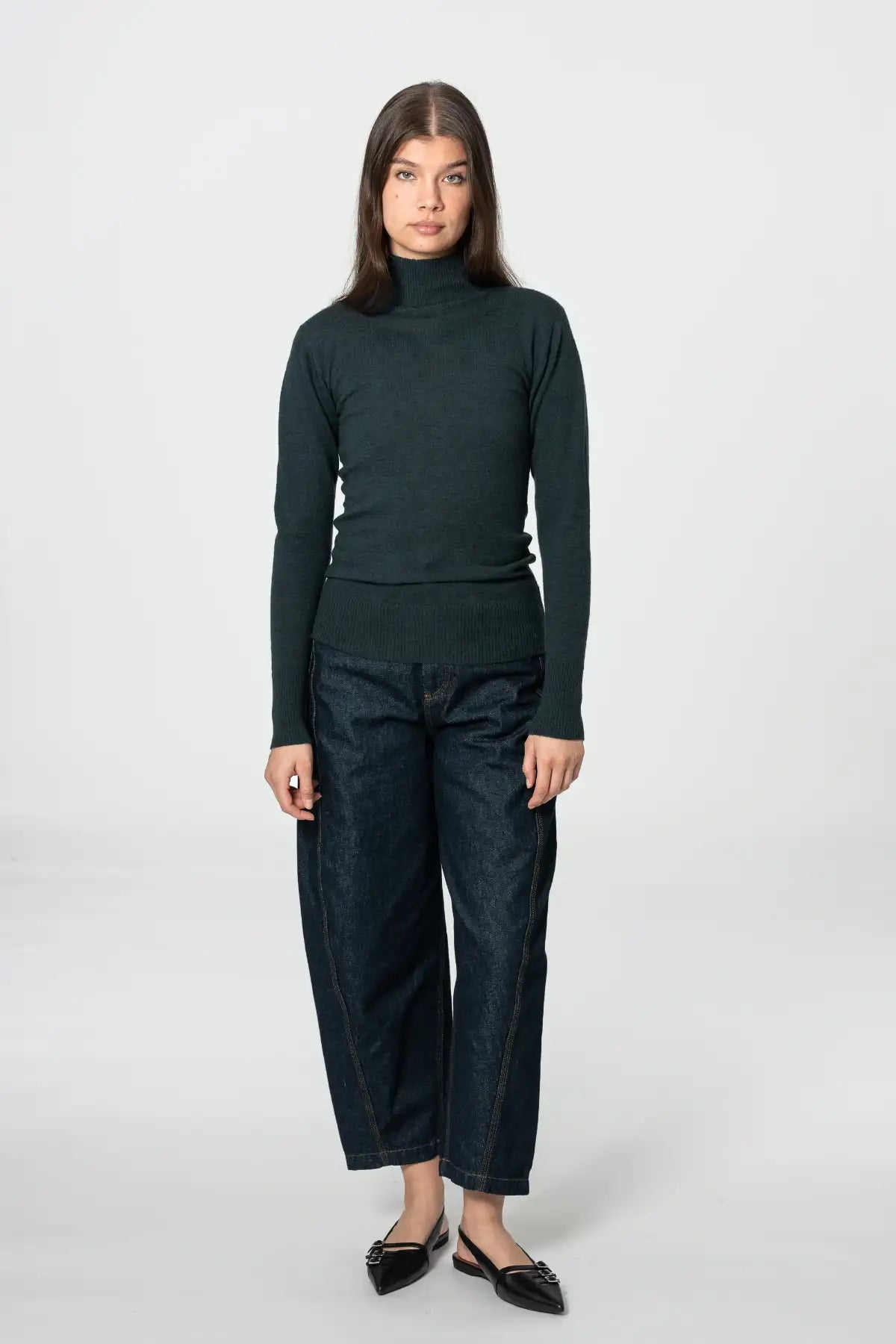 Dinadi women's merino turtleneck sweater in dark green, paired with high-waisted jeans