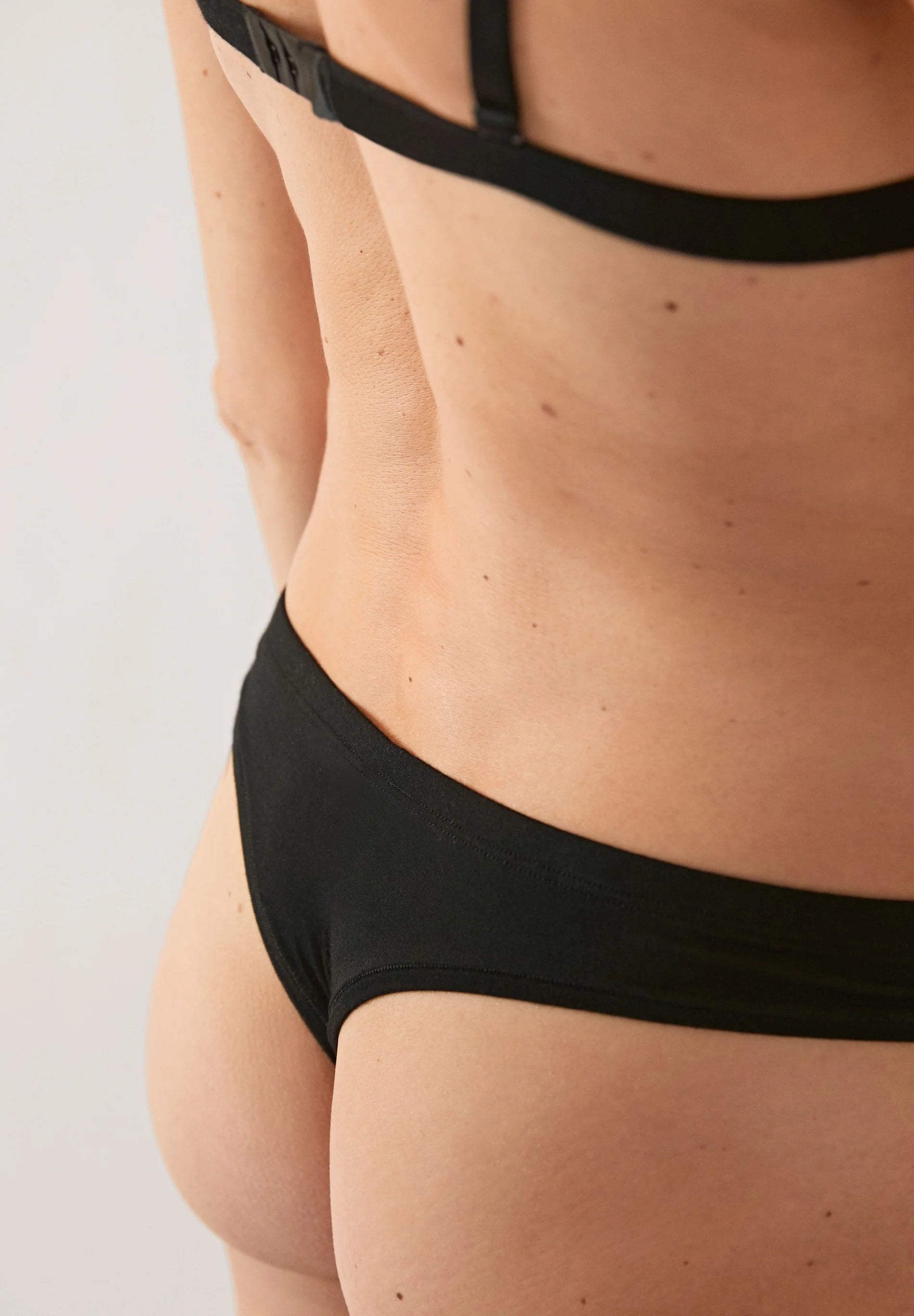 close up of FAARA String Underwear - ARMEDANGELS Canada bikini panties in black from back on model