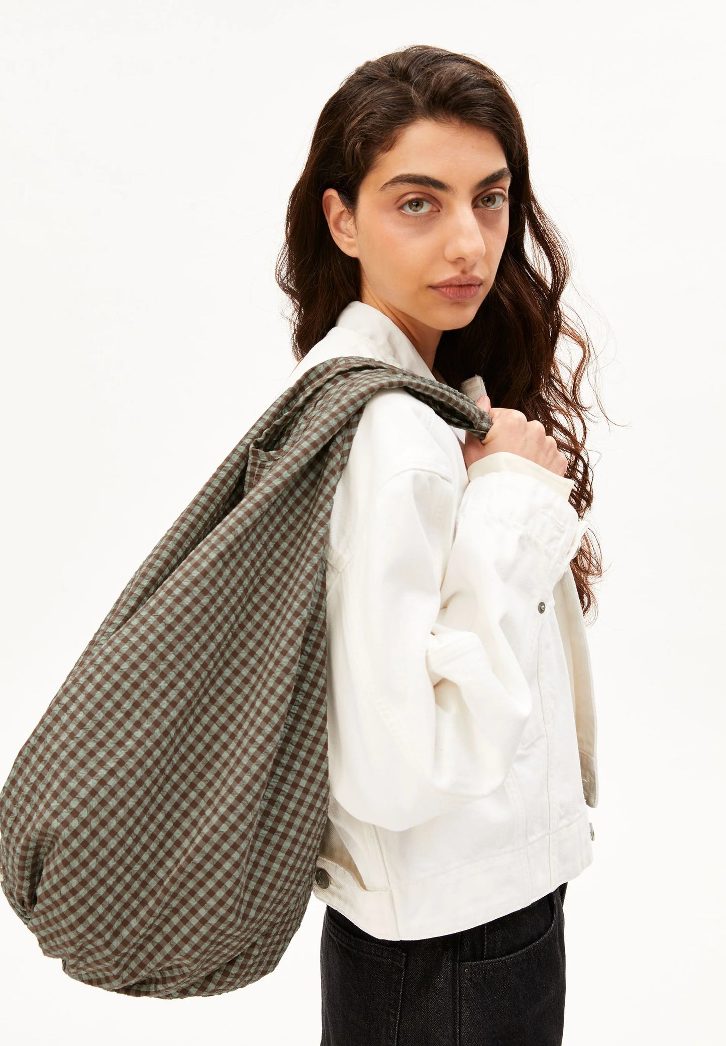 Close up of side shot of model holding brown and green checkered bag for Kelowna and Canada