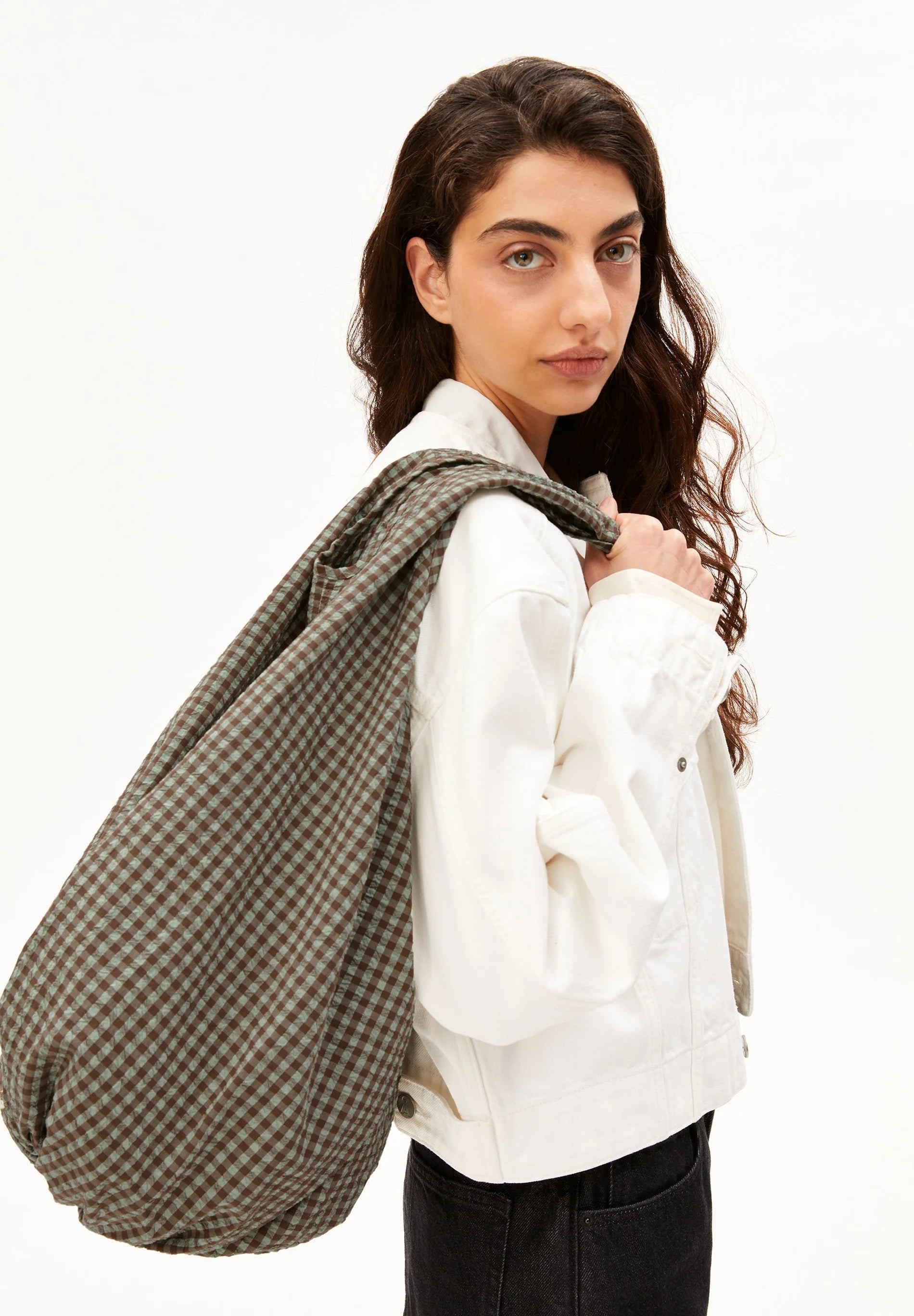 Close up of side shot of model holding brown and green checkered bag for Kelowna and Canada