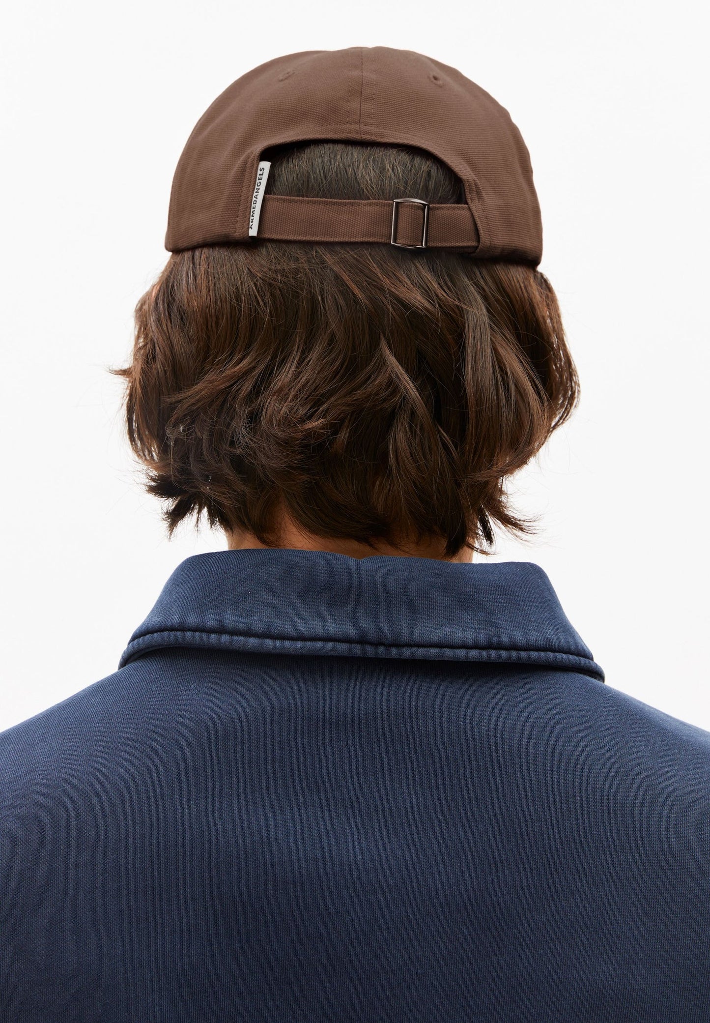 Person wearing a brown cap and navy jacket on a white background