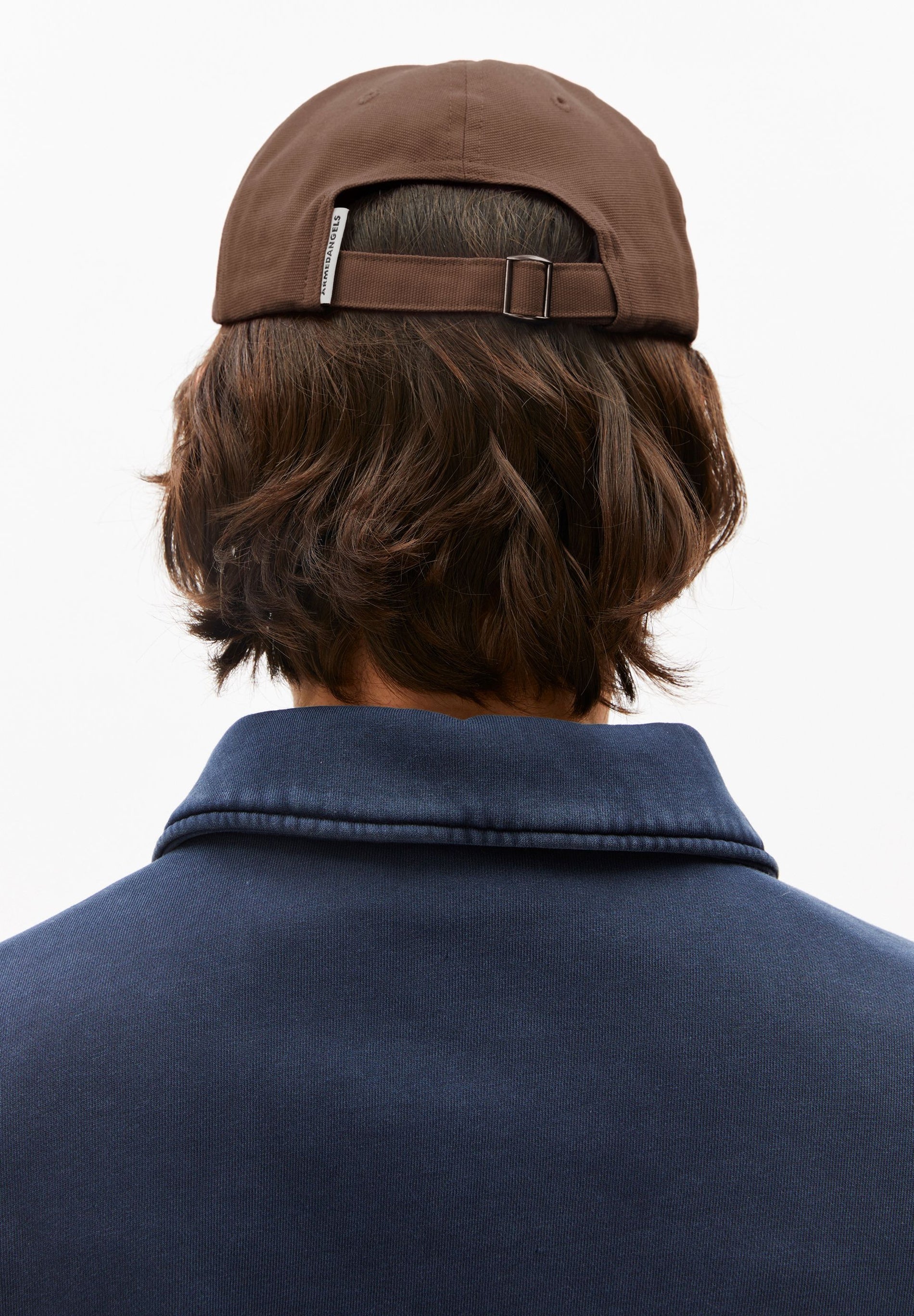 Person wearing a brown cap and navy jacket on a white background