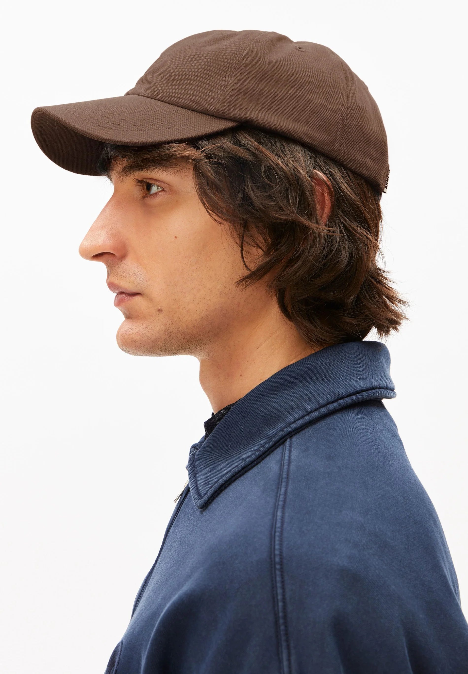 Man wearing a brown cap and blue jacket on a white background