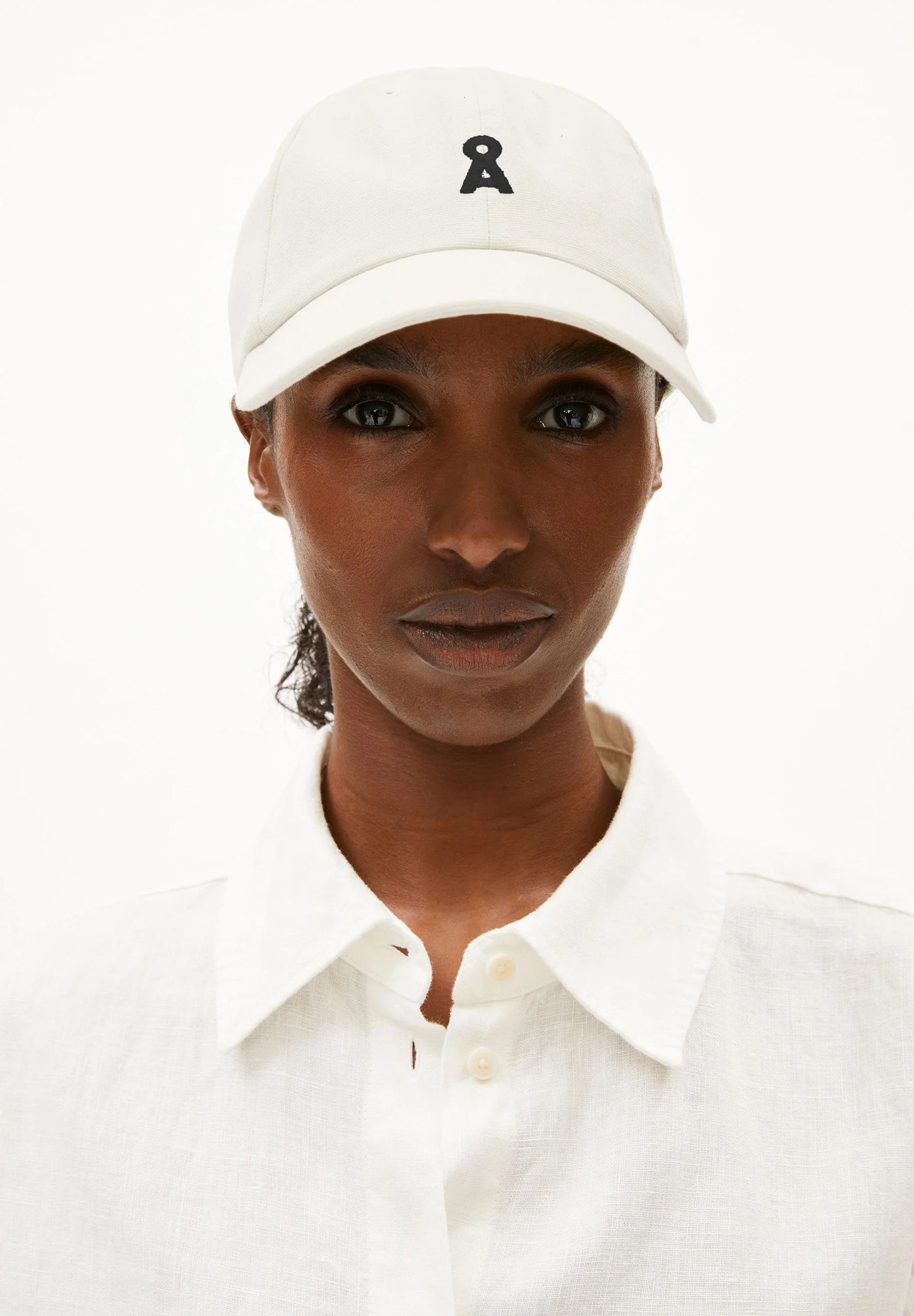 Person wearing a white cap with a logo on a white background