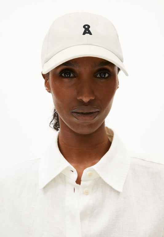 Person wearing a white cap with a logo on a white background