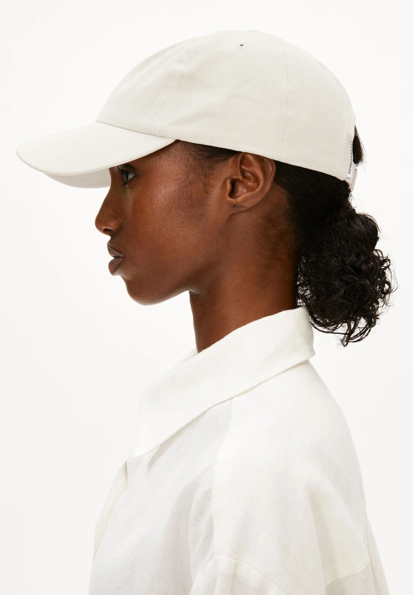 Person wearing a white cap and white shirt on a white background