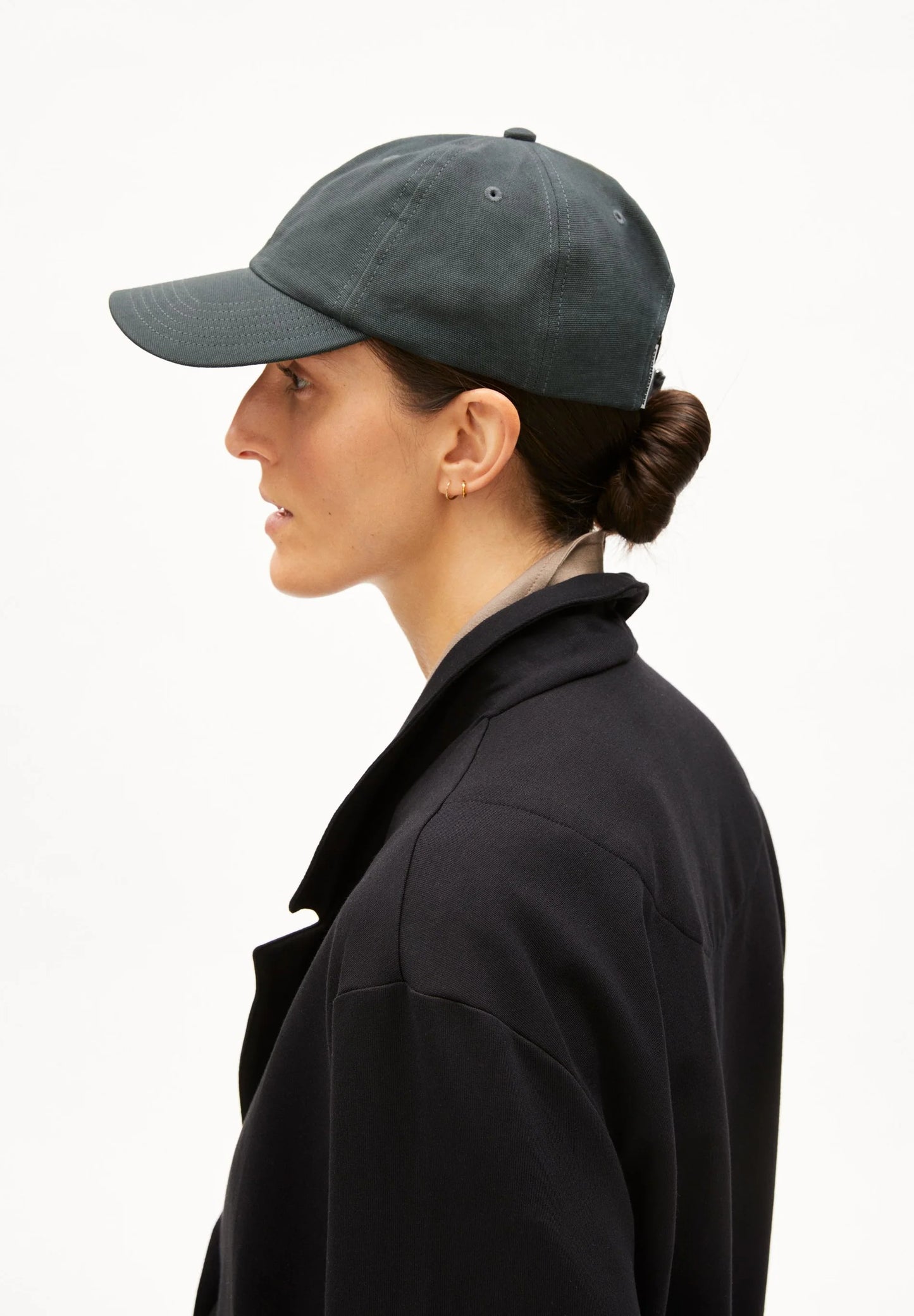 Person wearing a gray baseball cap and black jacket on a white background