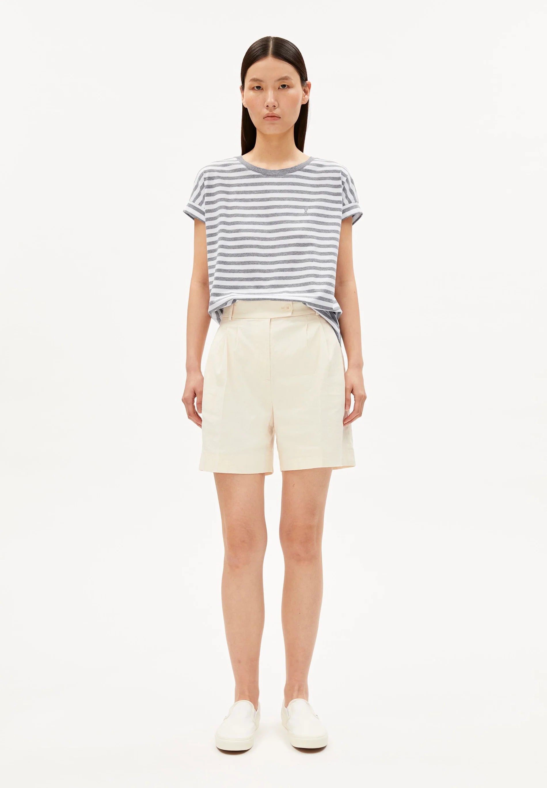 Woman wearing a striped shirt and cream shorts on a white background