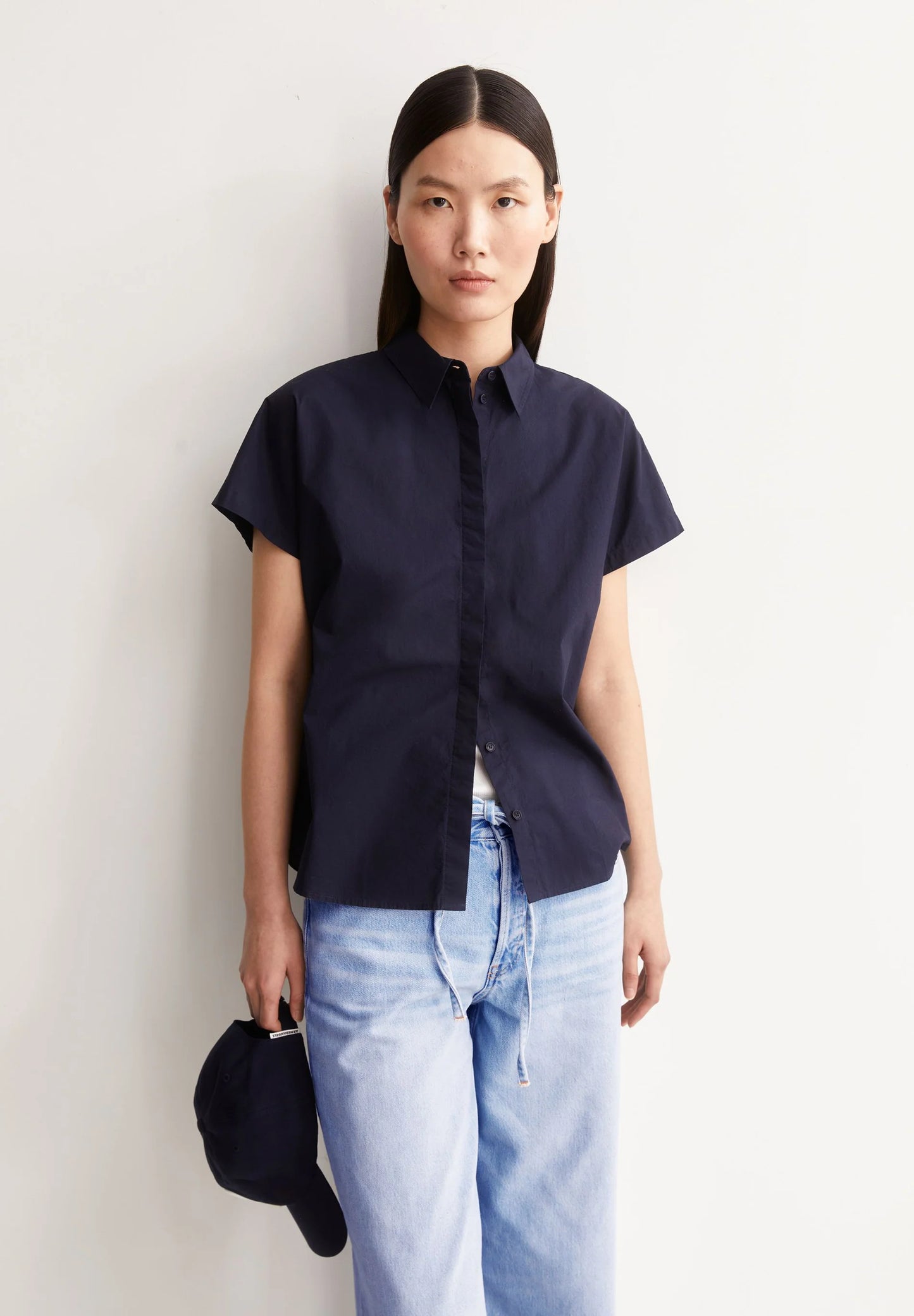 Person wearing a navy short-sleeve shirt and light blue jeans against a white background for Kelowna and Canada