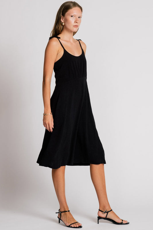 Allison Wonderland Manakin Dress in black, side view showing empire waist and adjustable tie straps on model in Kelowna