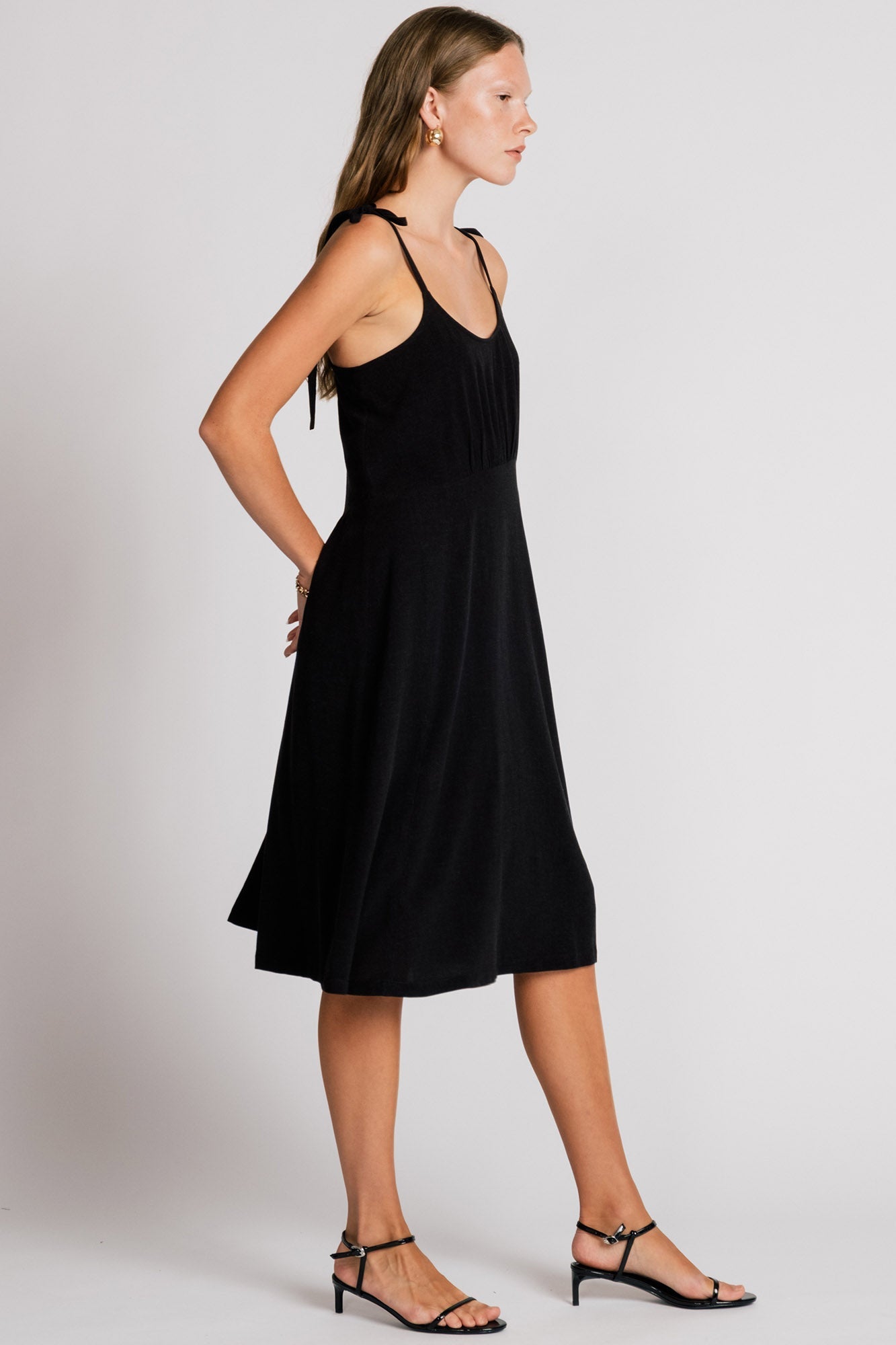 Allison Wonderland Manakin Dress in black, side view on model with white background, available at Textile Apparel Kelowna