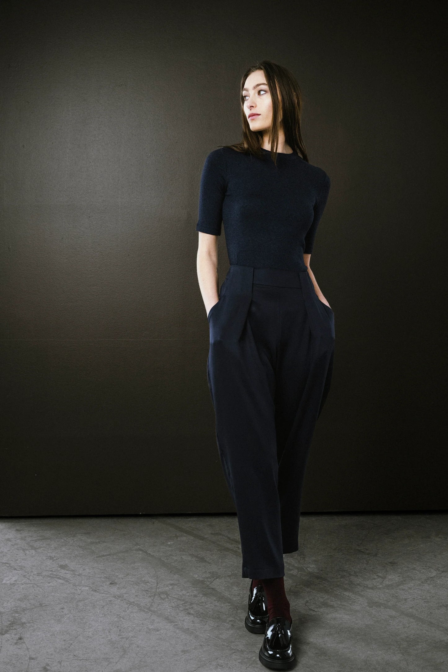Woman wearing a dark blue outfit against a black background