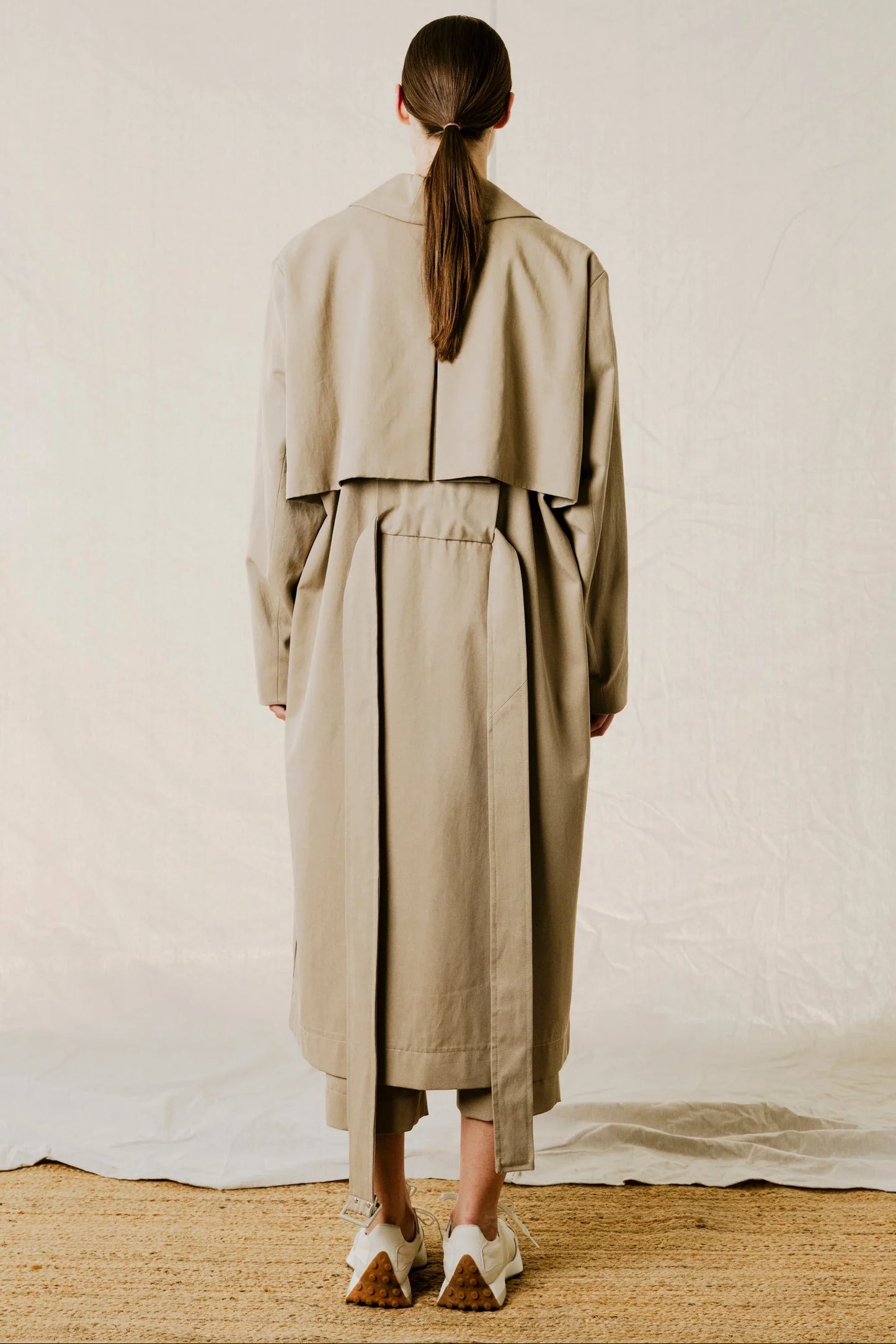 back view on model of District Trench Coat in Beige by Bodybag by Jude — oversized Tencel-cotton trench with removable belt, available in Kelowna at Textile Apparel
