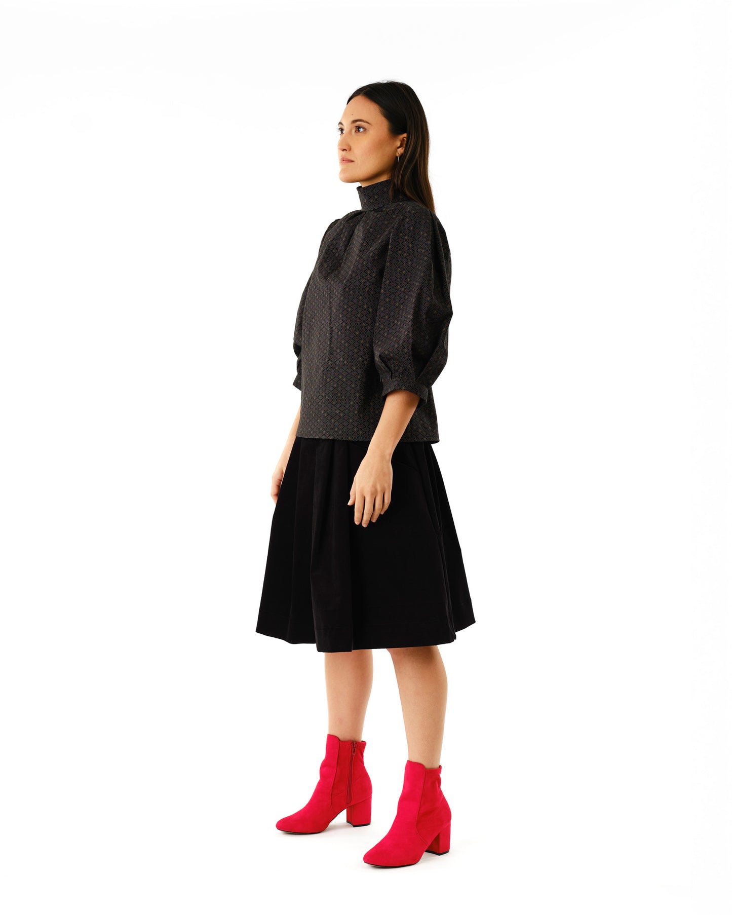Jennifer Glasgow Design model side profile wearing black polka dot high neck blouse black midi skirt red suede ankle boots in Kelowna