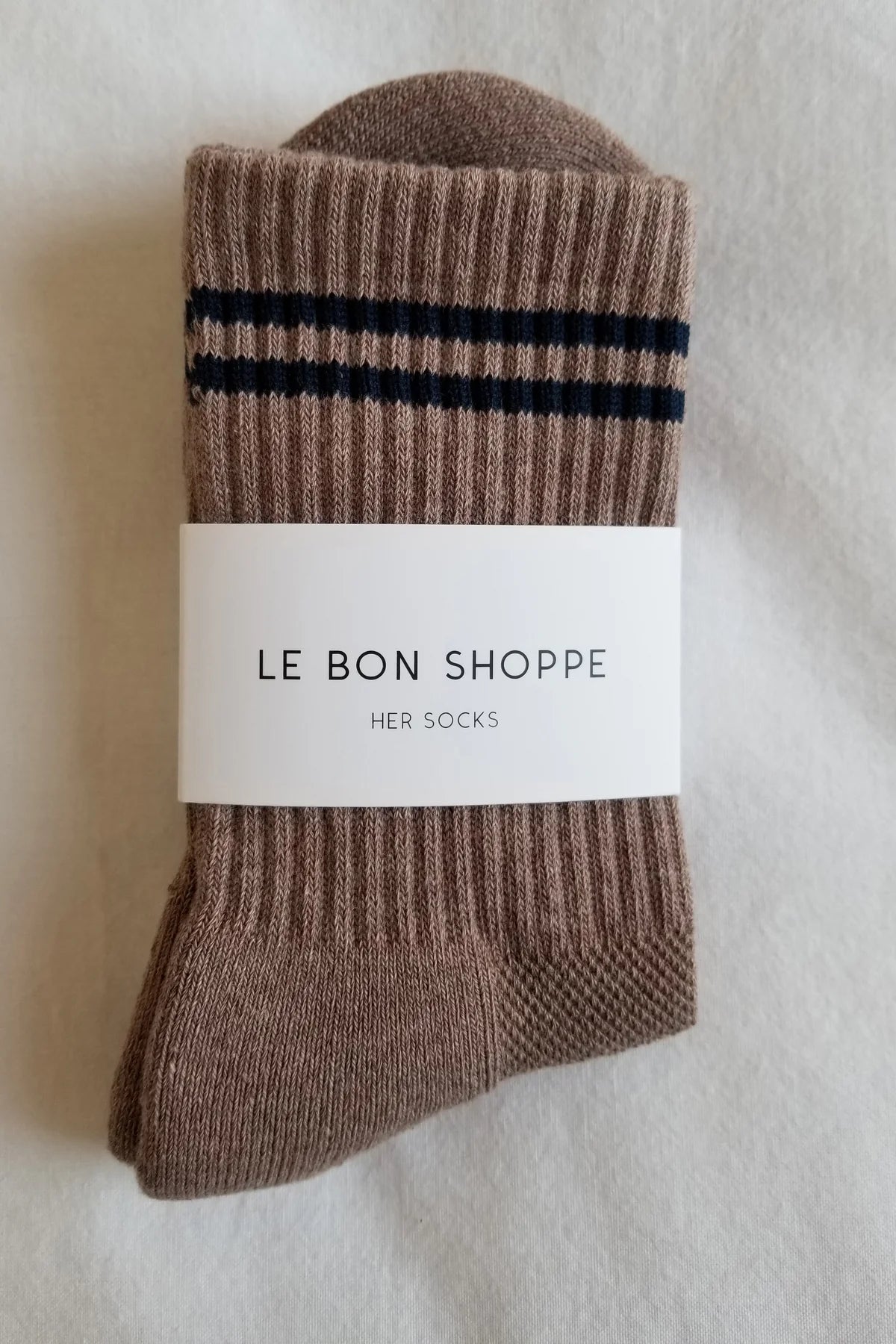 Brown sock with black stripes and 'Le Bon Shoppe' label on a light background