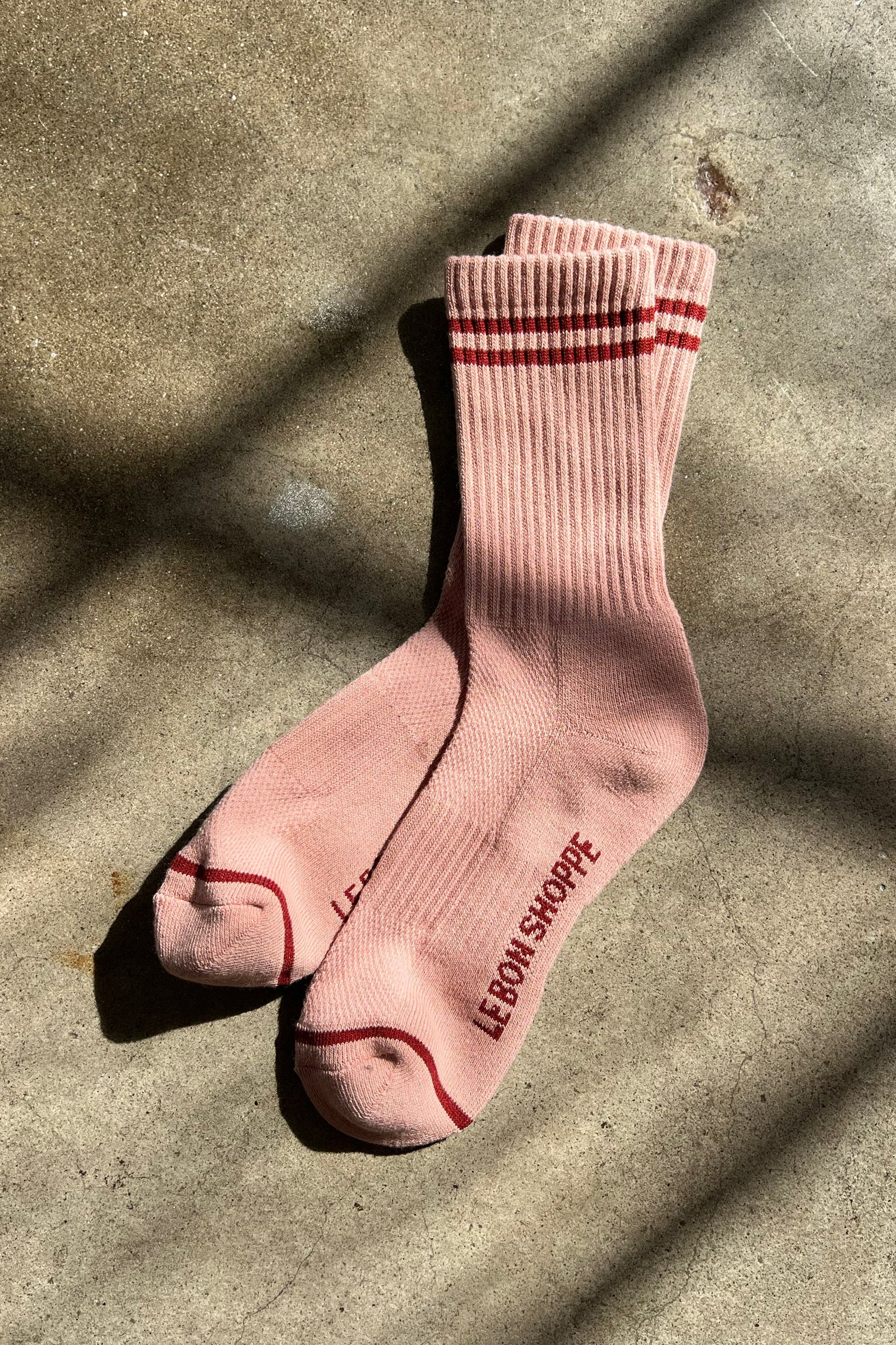Pink socks with red accents on a textured surface