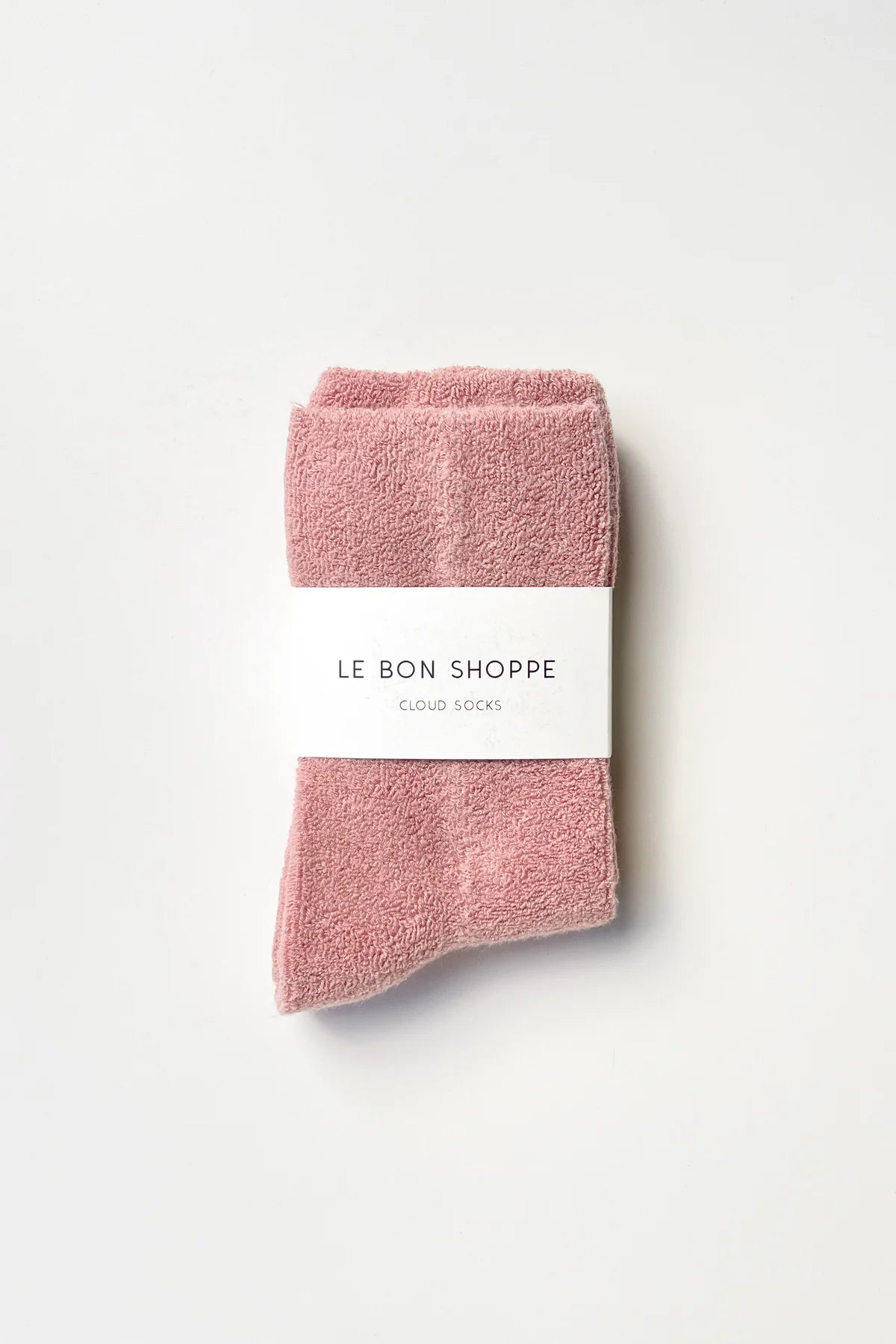 Folded pink socks with a white label on a light gray background