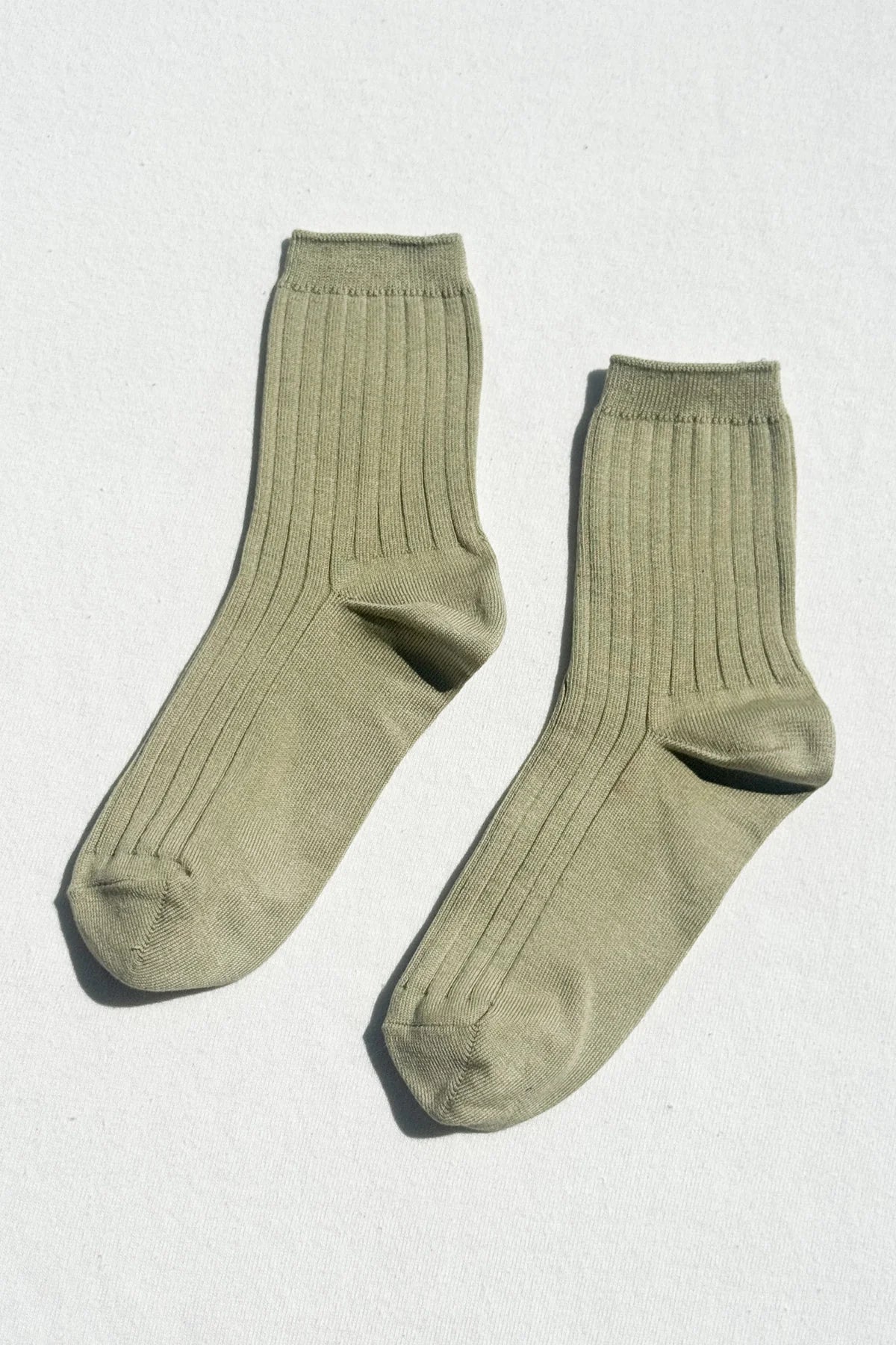 Pair of avocado green socks on a light gray background