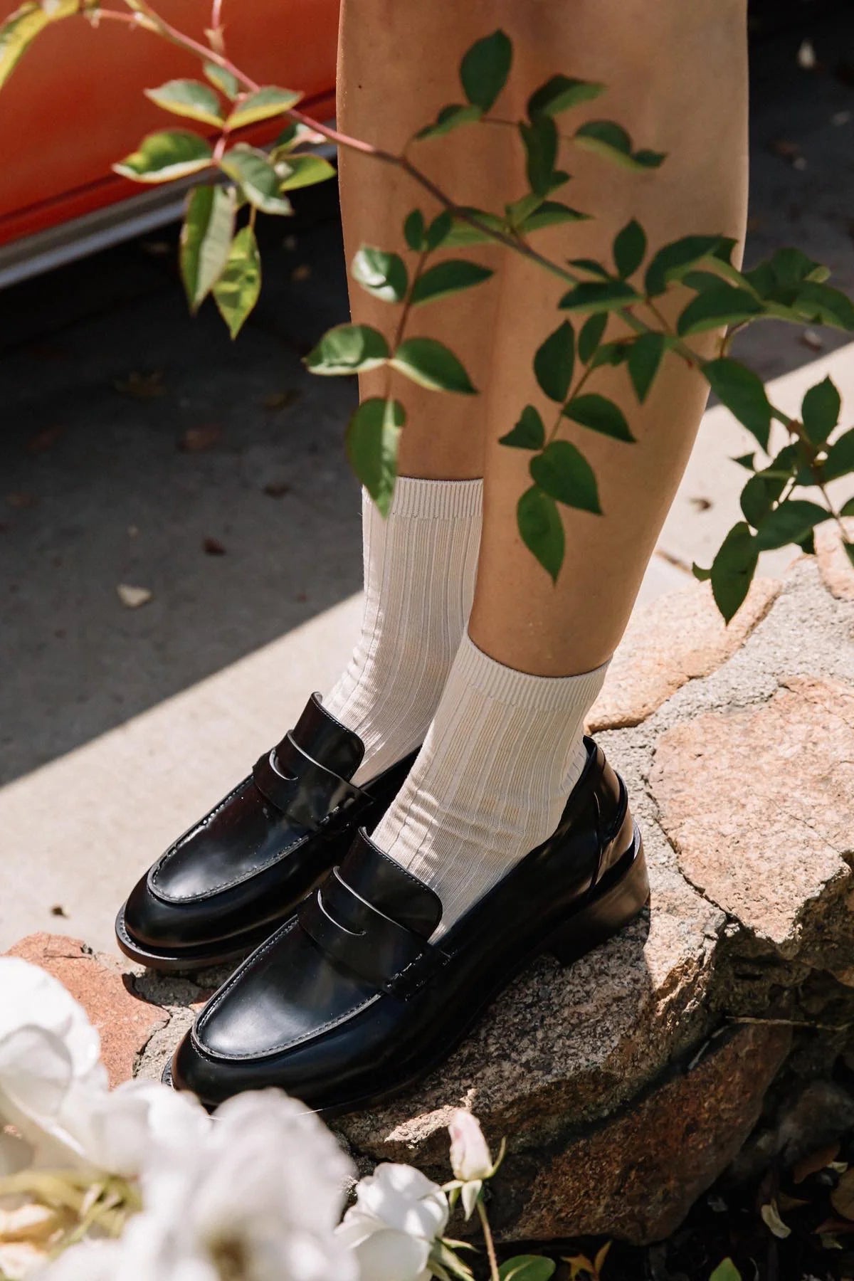 Person wearing black shoes and porcelain socks standing on a stone surface with greenery around in Canada.