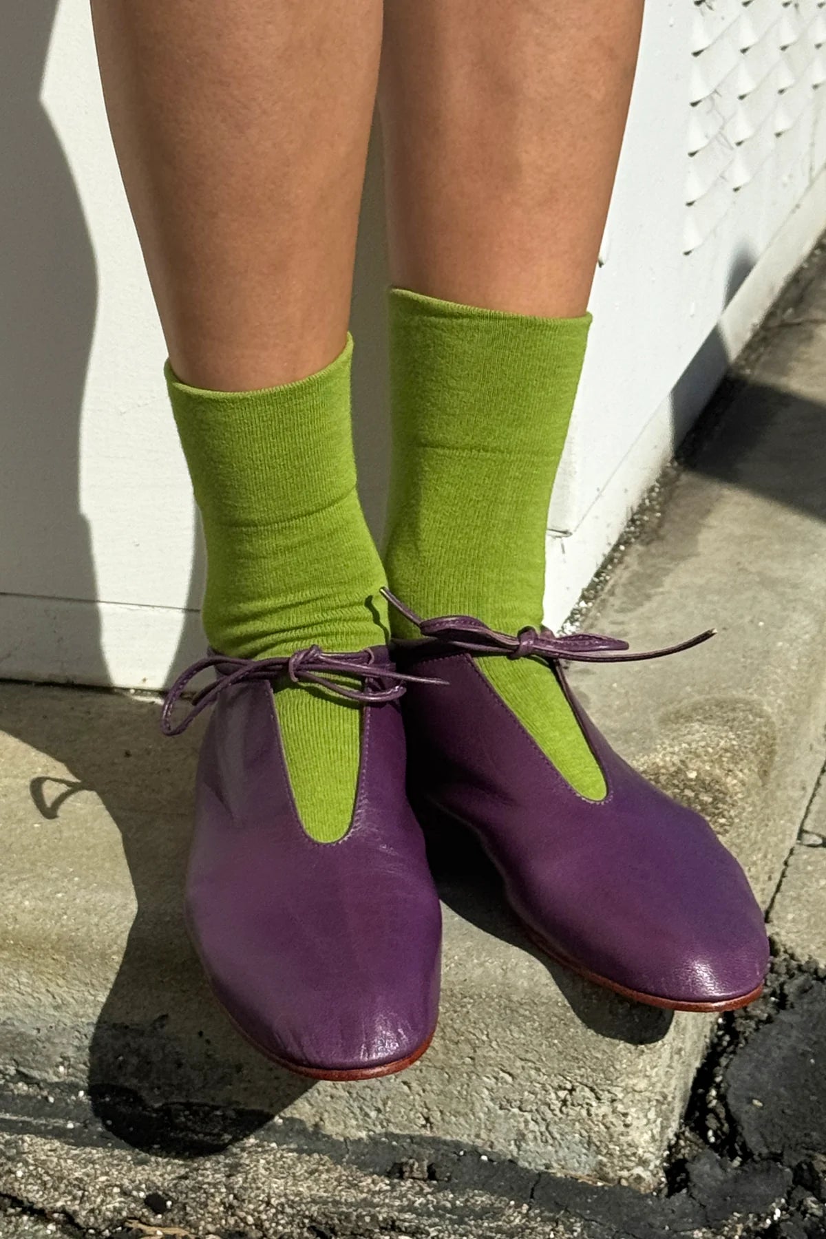 Purple shoes with green socks on a concrete surface