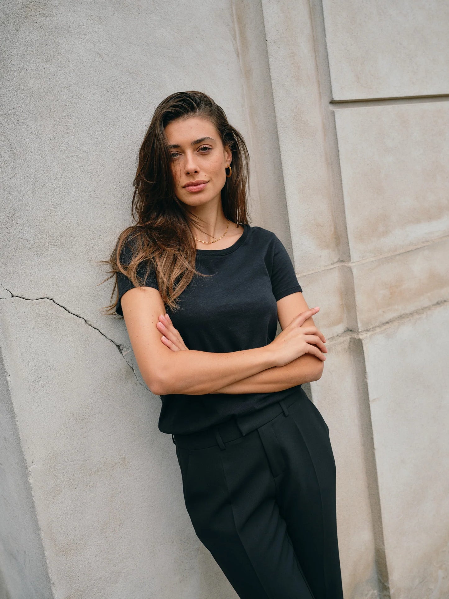 Woman in a black outfit standing against a textured wall
