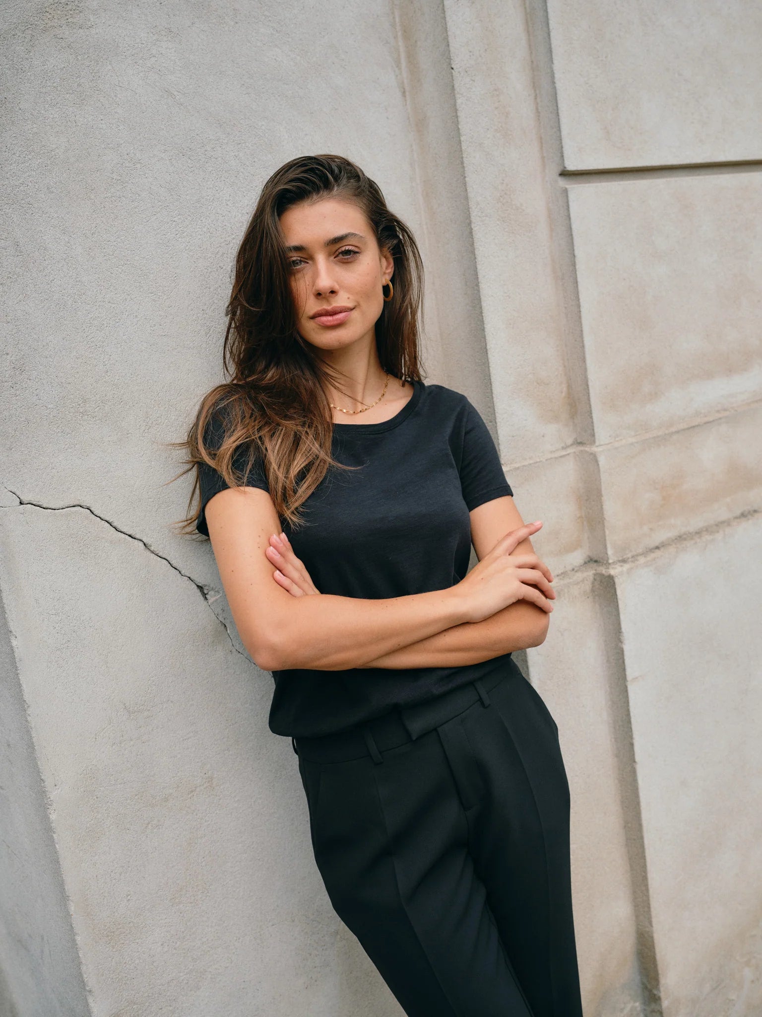 Woman in a black outfit standing against a textured wall