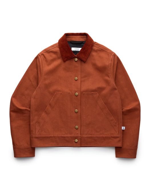 RED-ORANGE COTTON WORKWEAR JACKET WITH A RED-ORANGE CORDUROY COLLAR, LAID FLAT AGAINST A WHITE BACKGROUND