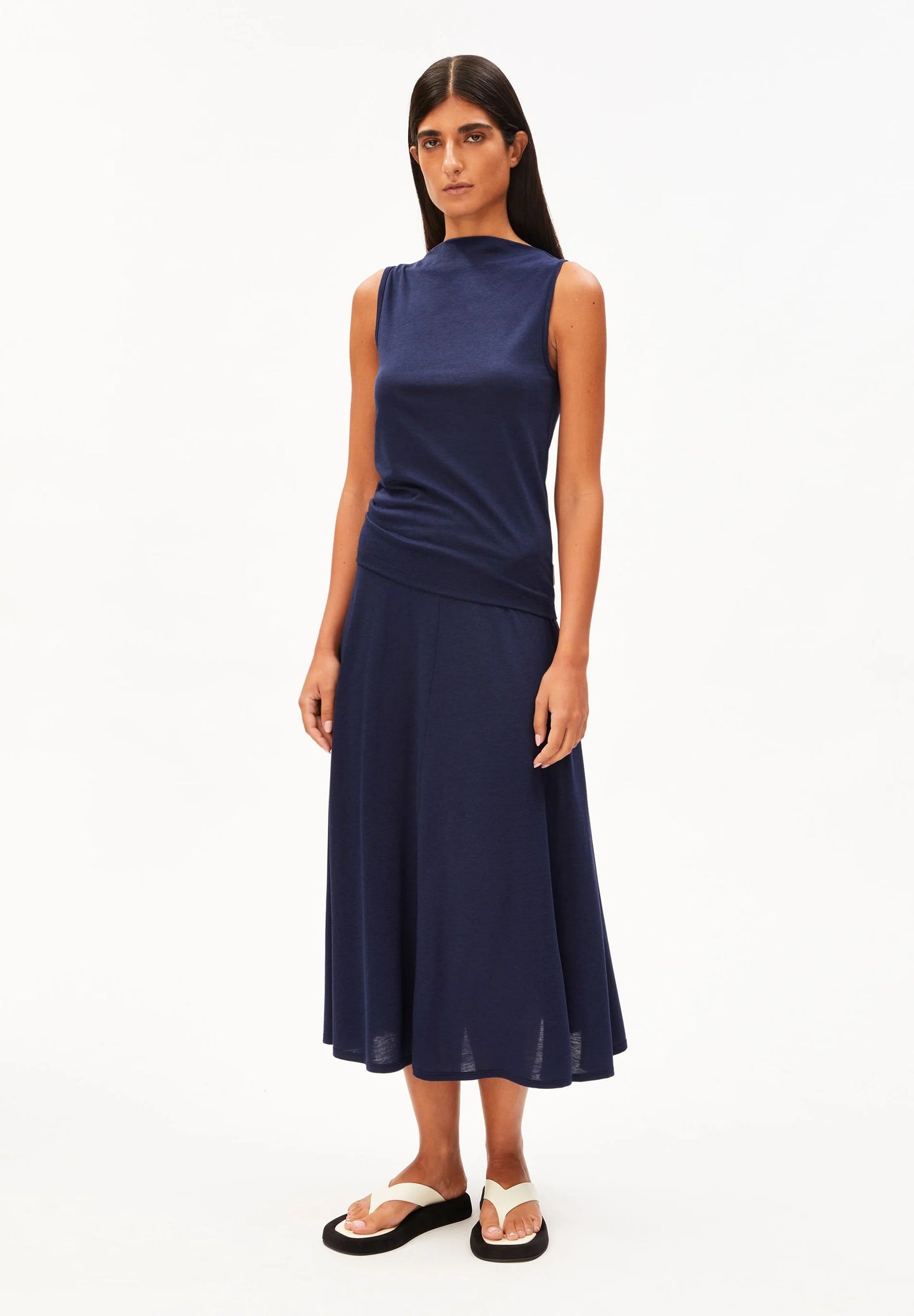 woman wears navy shirt and skirt against white background