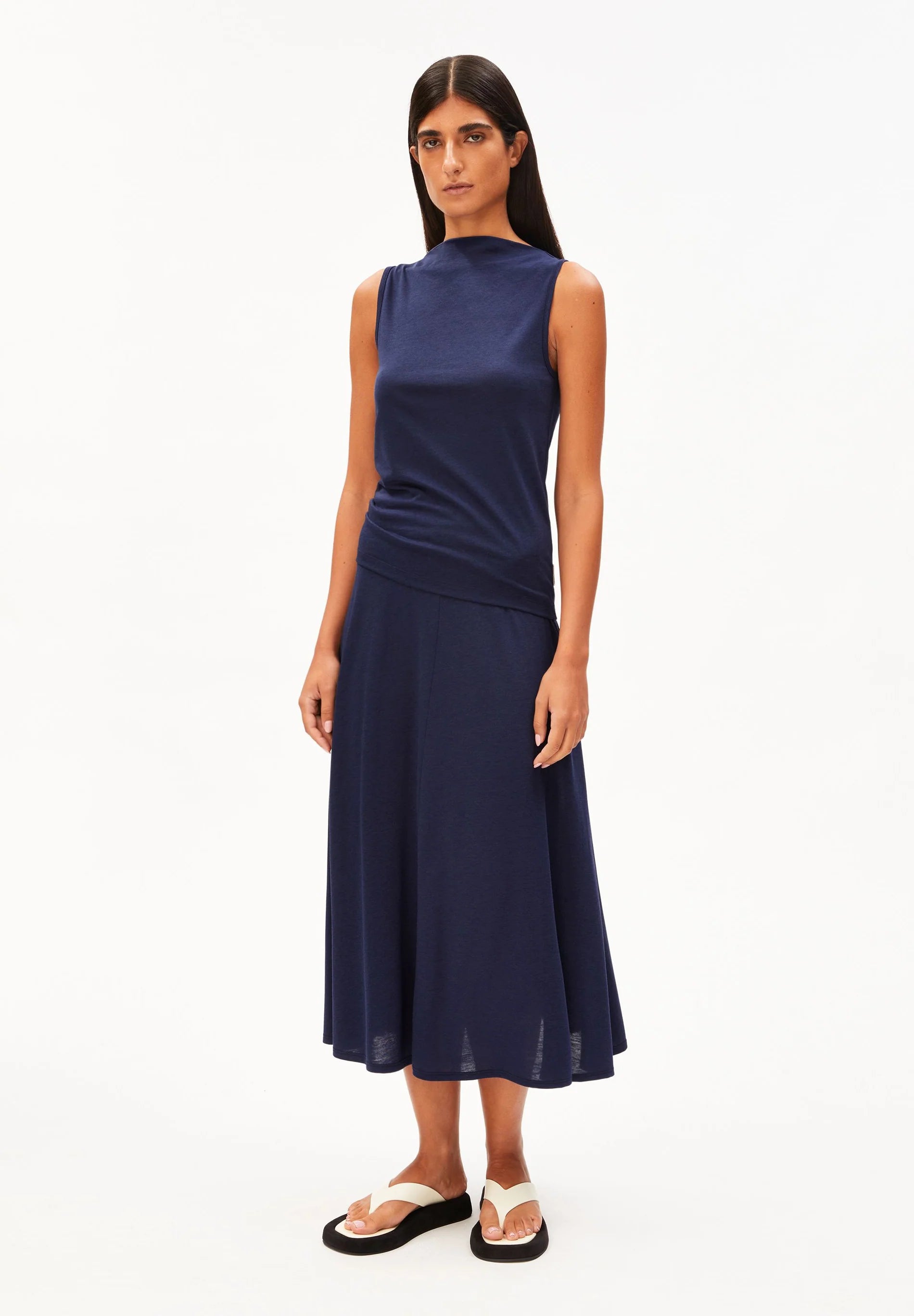 woman wears navy shirt and skirt against white background