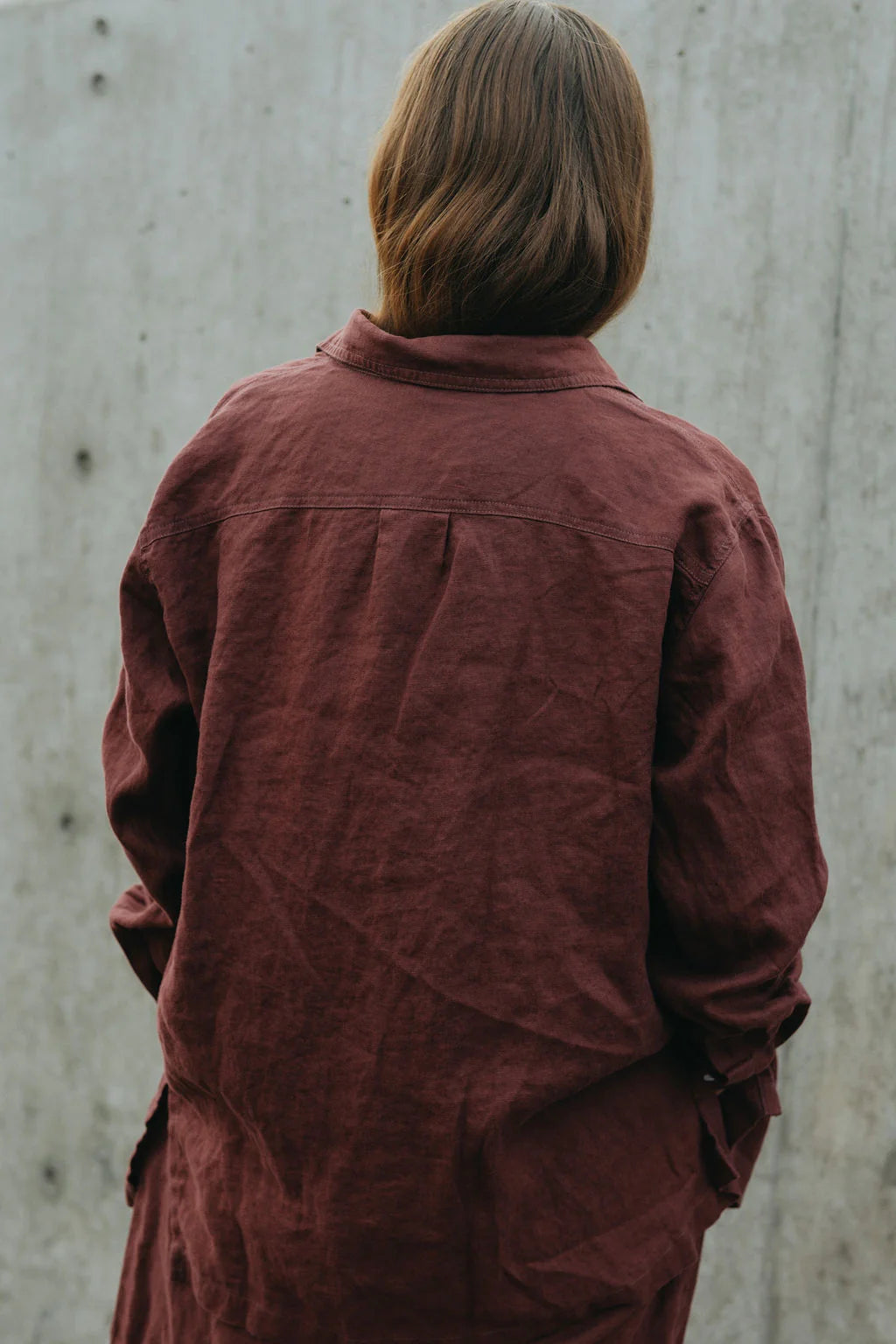 Person wearing a maroon jacket against a plain background