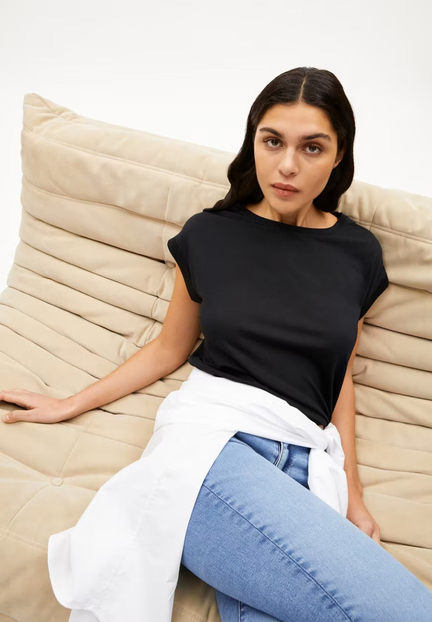 ARMEDANGELS Canada - black casual short sleeve t-shirt worn by model sitting on beige couch in Kelowna