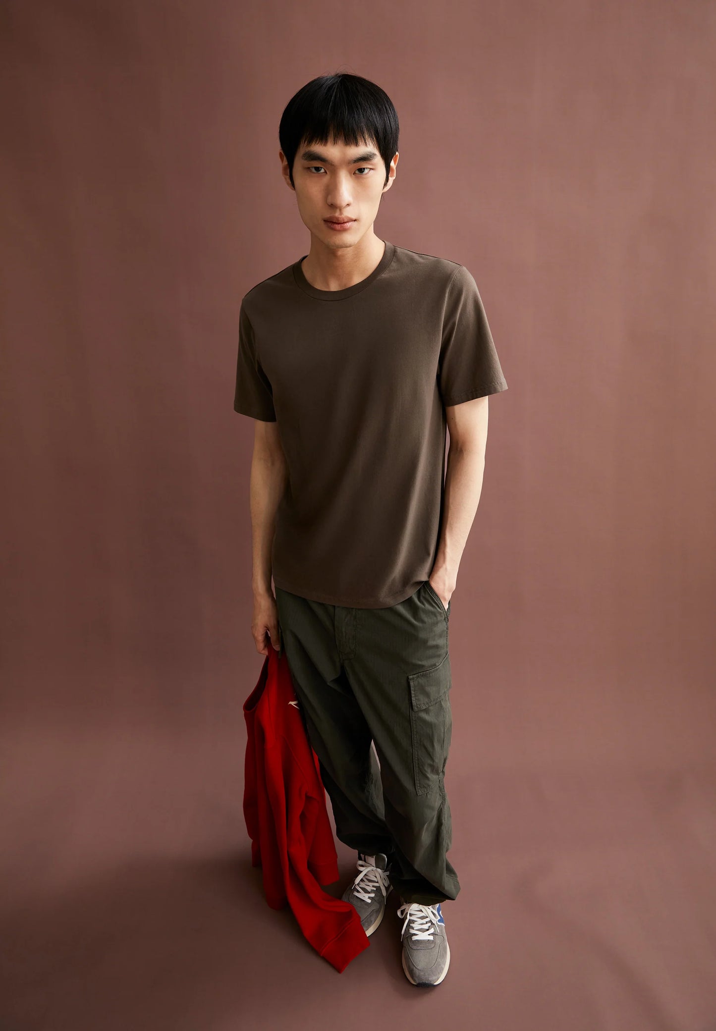 Men's ARMEDANGELS t-shirt in brown, styled with relaxed pants and a red jacket in Kelowna