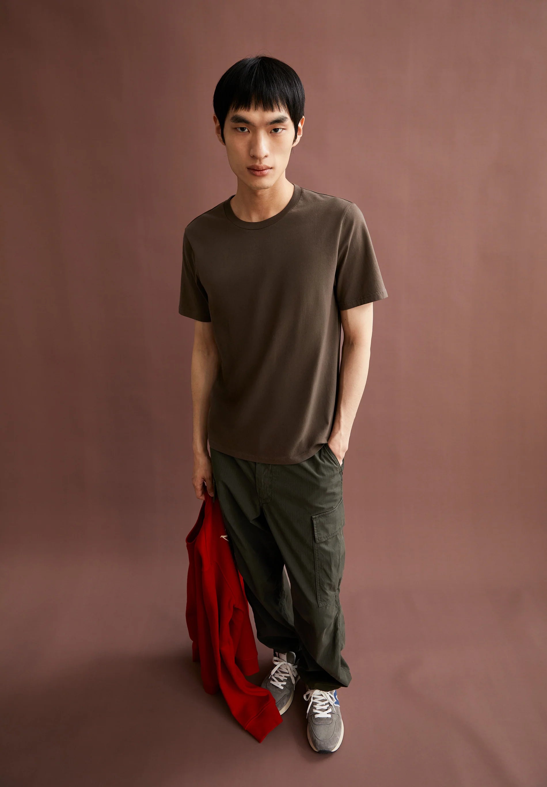 Men's ARMEDANGELS t-shirt in brown, styled with relaxed pants and a red jacket in Kelowna