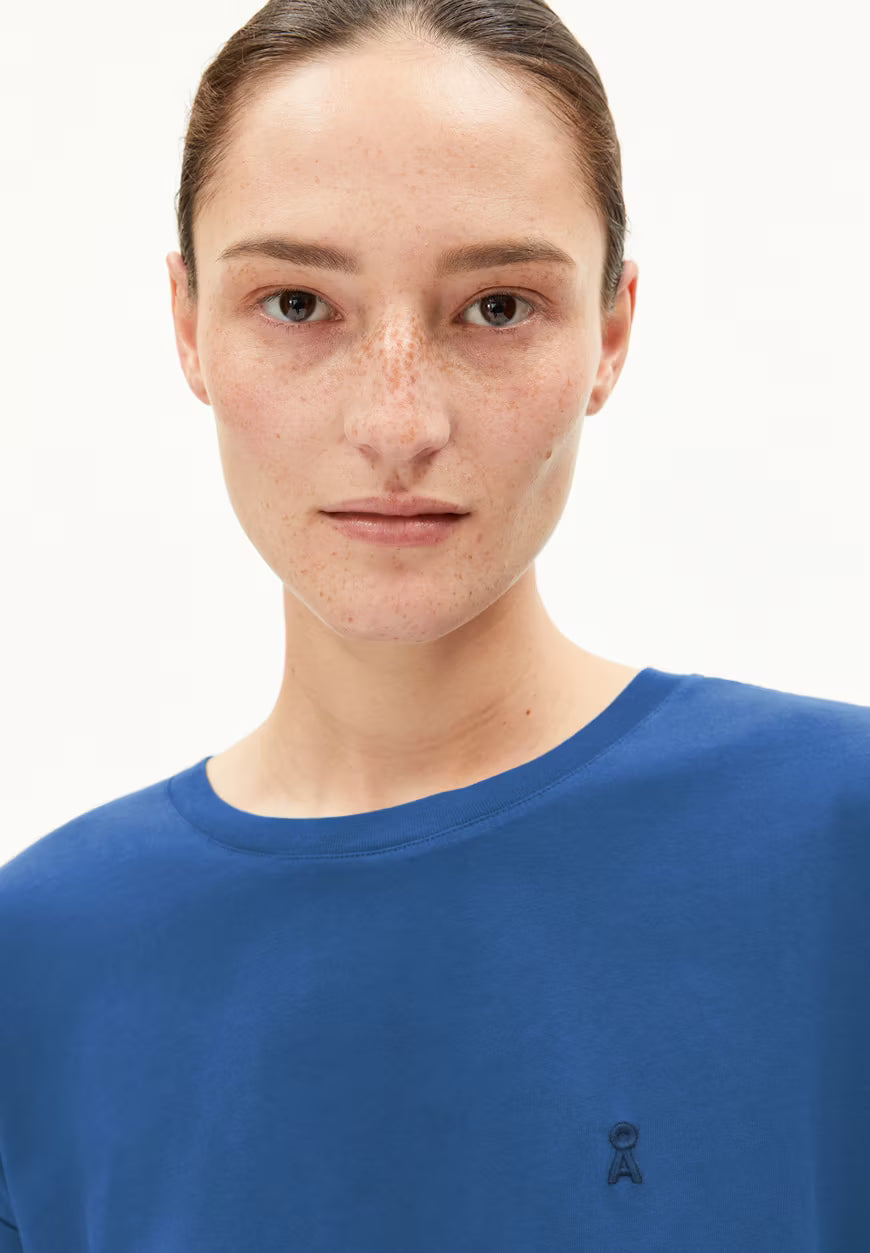 Close-up of woman wearing a blue ARMEDANGELS t-shirt with minimalist logo on the chest in Kelowna