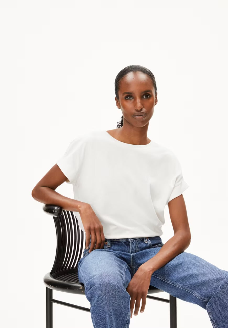 ARMEDANGELS Canada white short sleeve blouse paired with blue jeans worn by seated model in Kelowna