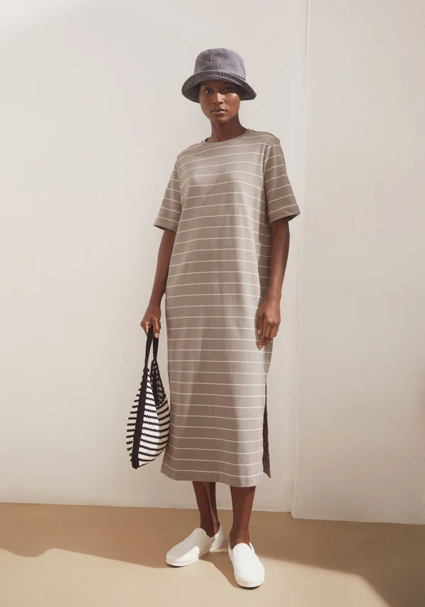 Styled model wearing ARMEDANGELS Canada long light brown t-shirt dress with a grey hat and black and white striped 